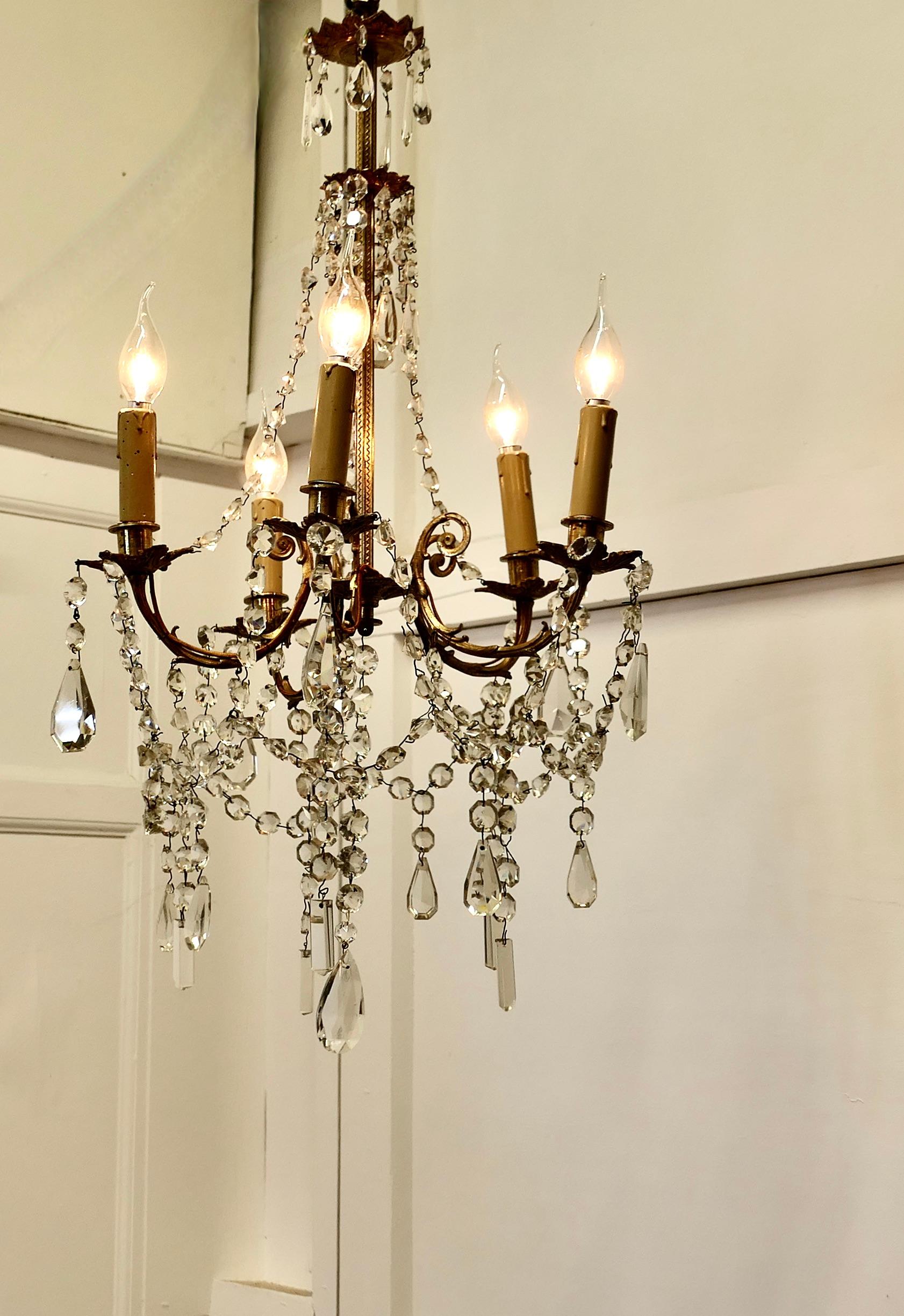 Large French Crystal and Brass 5 Branch Chandelier

This is an excellent quality piece, the decorated brass centre column supports the scrolling branches, the 5 arms are hung with many strings of beads and flat crystal pendants and more hanging from