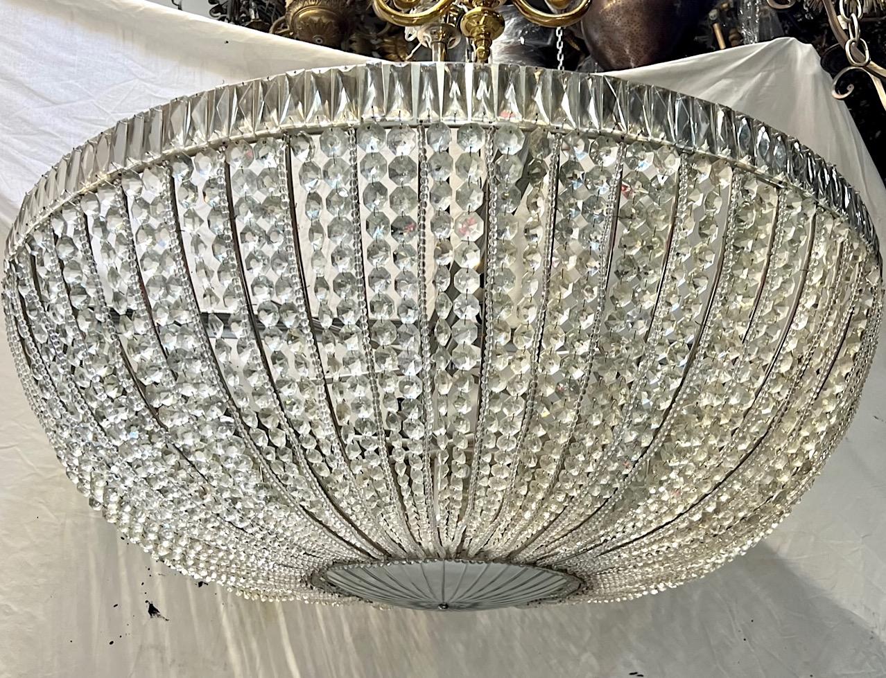 A French circa 1940's large crystal light fixture with silvered body, cut and mirrored crystal bottom inset and twenty-four interior candelabra lights.

Measurements:
Diameter: 48
