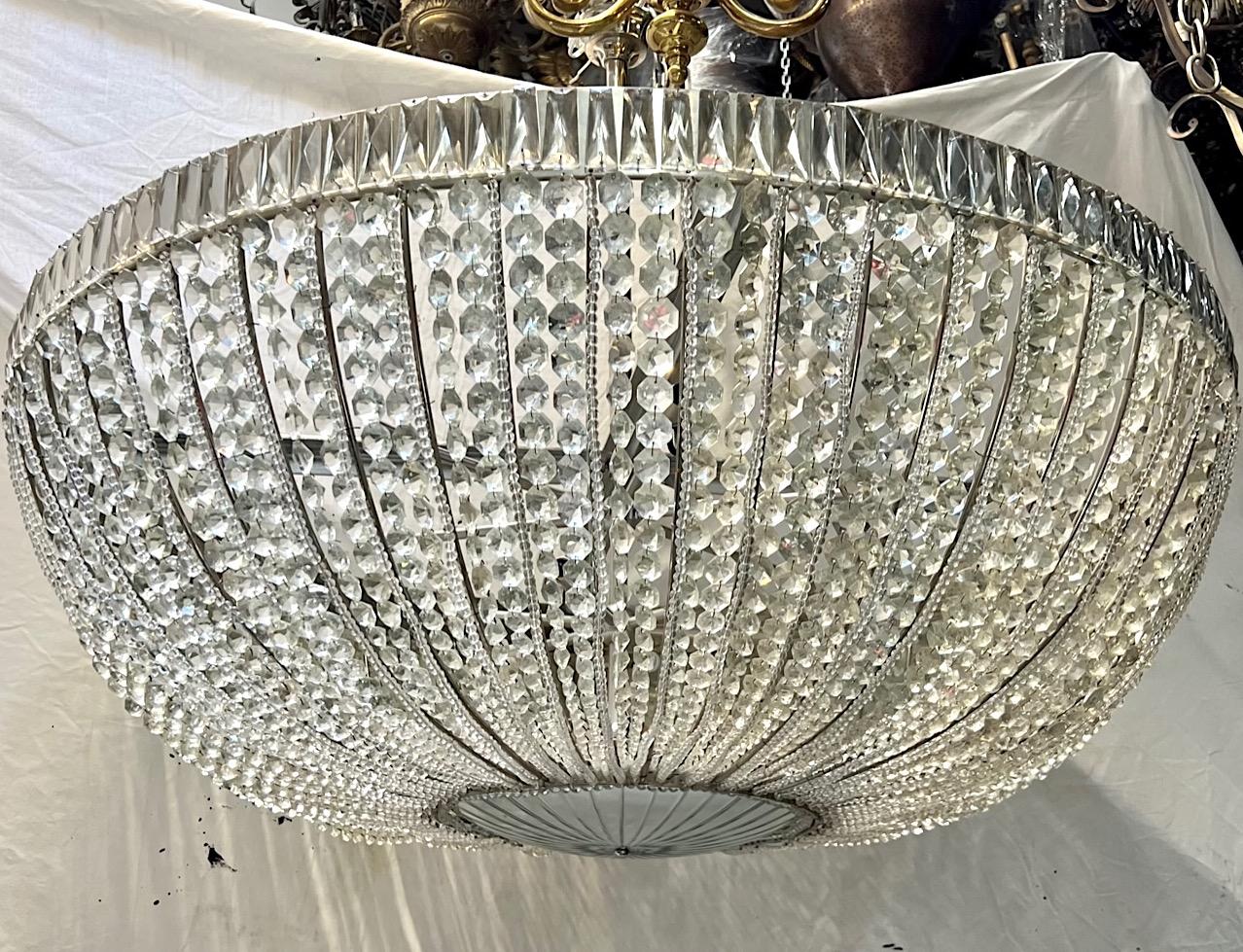 Grande lampada in cristallo francese degli anni '40 circa con corpo argentato, inserto inferiore in cristallo tagliato e specchiato e ventiquattro luci interne a candelabro.

Misure:
Diametro: 48