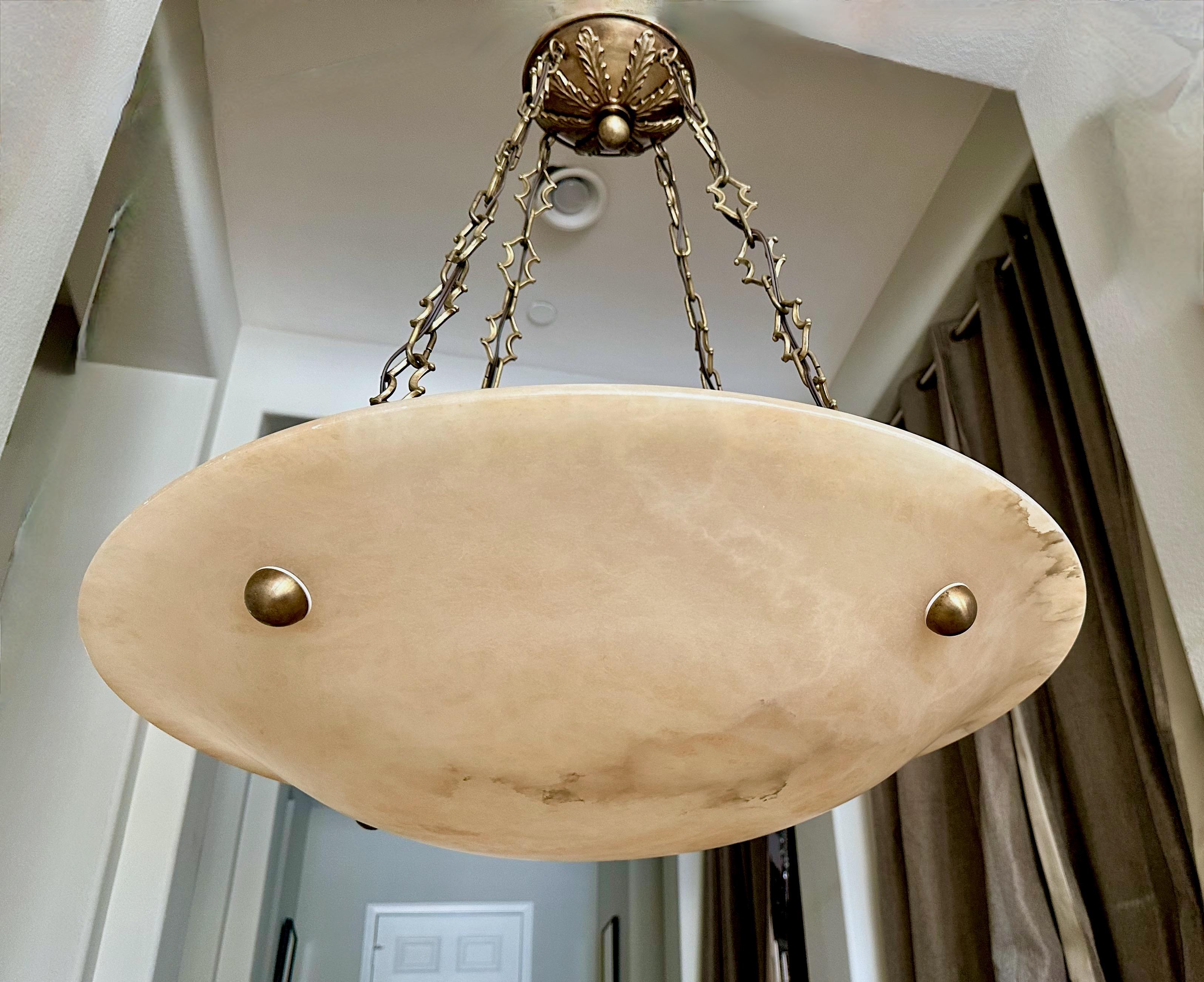 Lampada a sospensione o lampadario in alabastro di grandi dimensioni con finiture in ottone patinato invecchiato in stile Directoire. La pietra di alabastro è di un color crema chiaro con molte venature interessanti. Cablata di recente per gli Stati