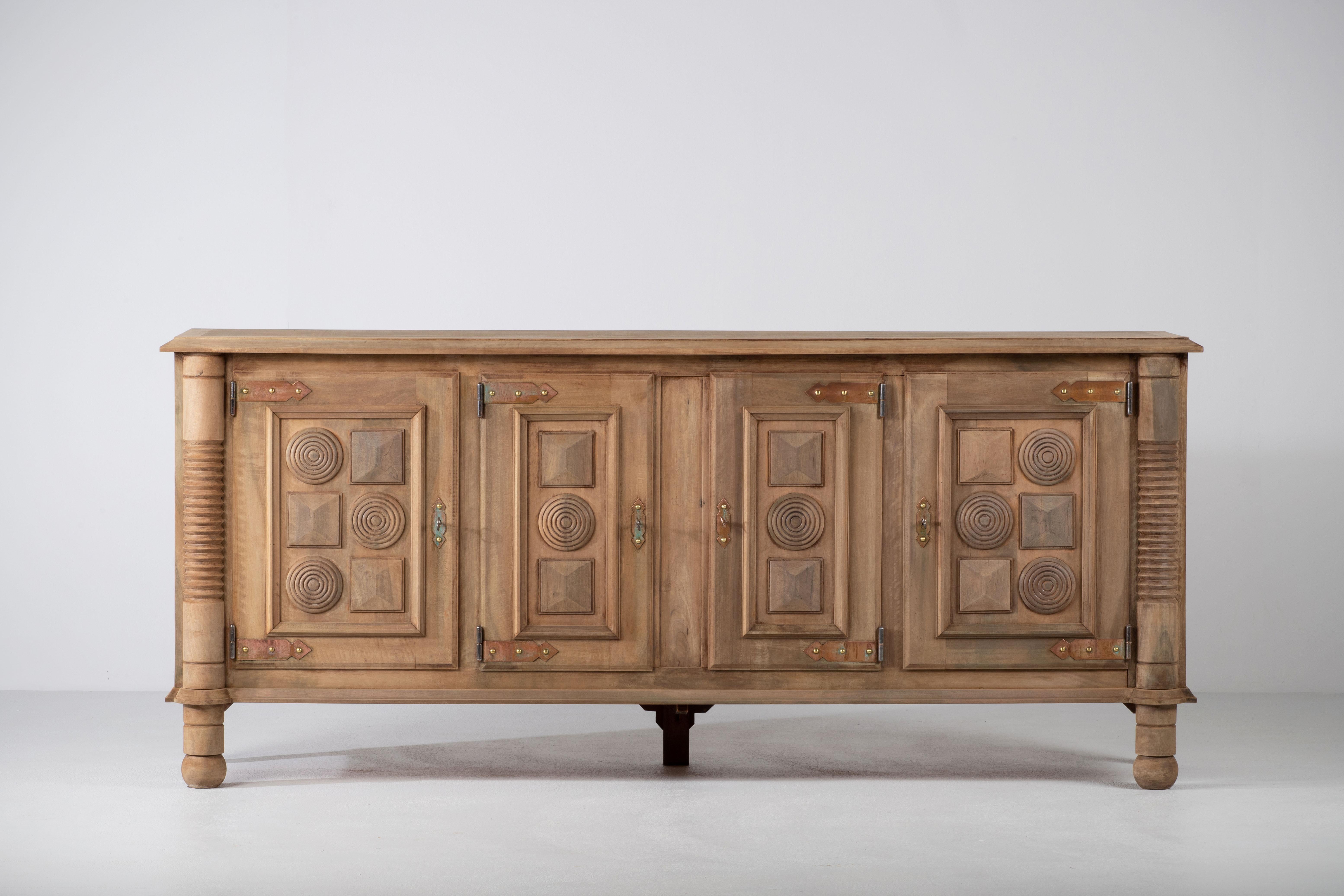 A large sideboard/credenza in solid natural oak attributed to Charles Dudouyt, France, circa 1940s.
Consists of 3 central drawers and two storage compartments. 
Original brass detailing and graphic design doors make this piece really stand