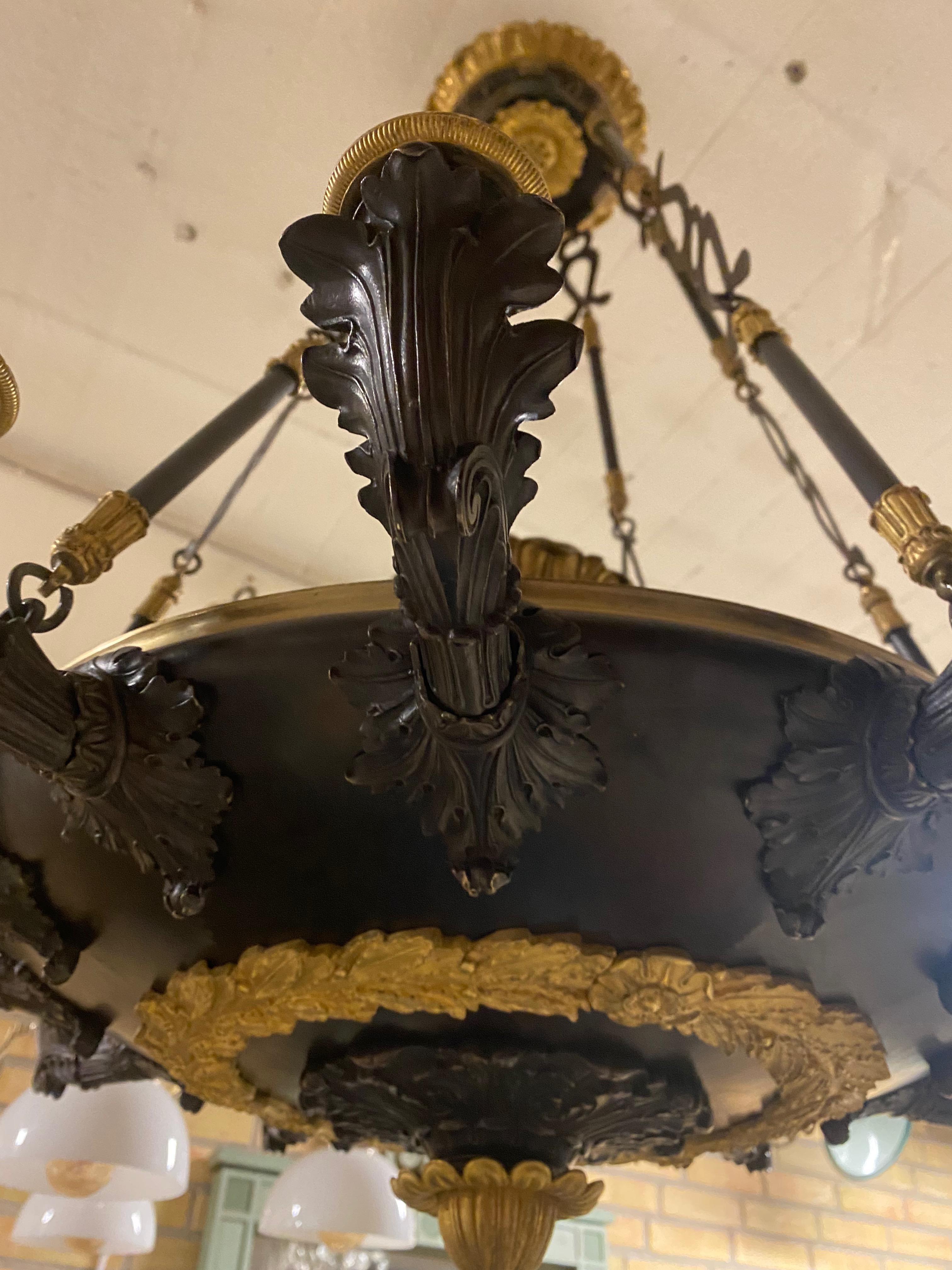 A large twelve armed chandelier made around 1820-30. The saucer shaped bowl is made of copper and patinated black. The 12 candlers are all cast of bronze and patinated black. 
A great piece for any interior. It is not electrified but this can be