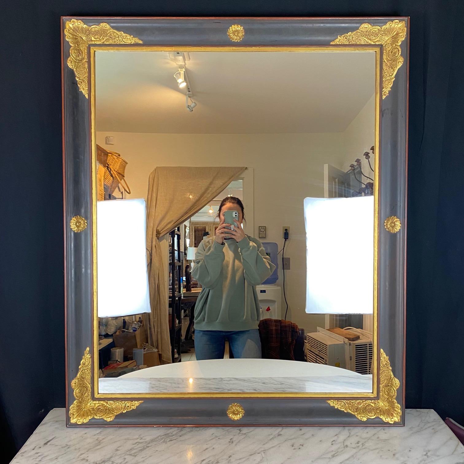 Large scale Empire gold gilt and ebony black mirror is a large statement piece. The giltwood finish is complemented by a lovely ebony black washed gesso patina. The neoclassical embossed motif is a classic French form. A lovely rectangular shape,