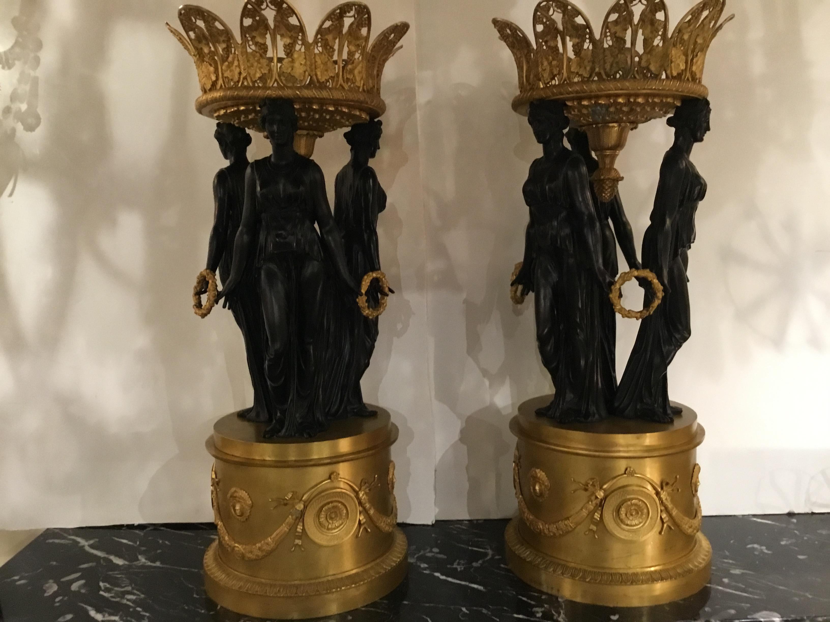 Pair of exquisite monumental centerpieces with bronze work in the the 
Manner of Pierre-Philippe Thormire, 1751-1843.  The pair in the form of reticulated gilt grape vine baskets sit at the crest of three classically draped maidens. They hold the