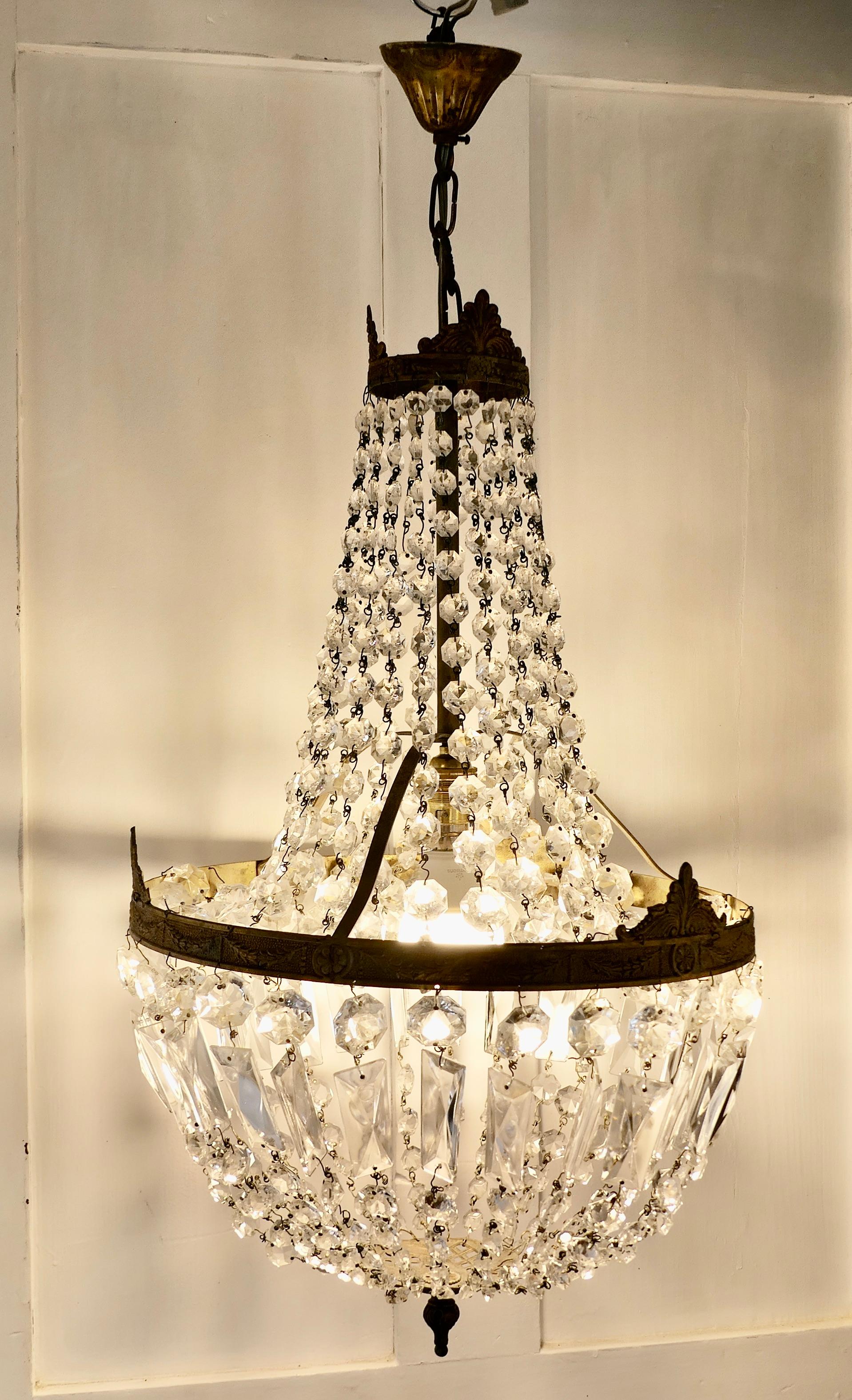 Large French Empire Style Tent chandelier

This is a lovely piece, quite a large chandelier, it has an aged brass frame hung with large crystals, completed at the bottom with a basket of multi faceted crystal drops

The lamp is in good working