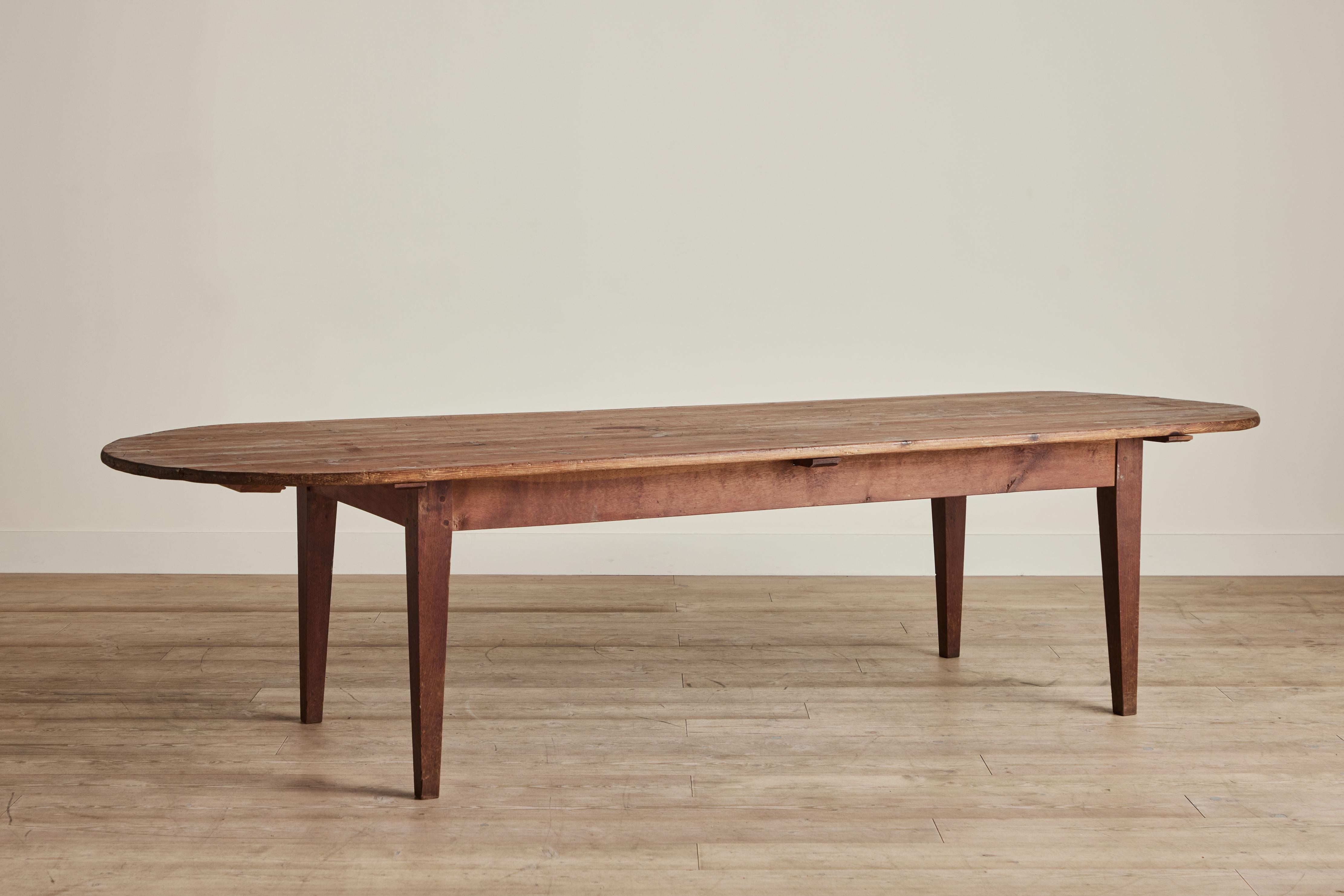 Rustic wood dining table from France circa 1900. This large oval top table measures 118 inches in length. Wear throughout on wood is consistent with age and use. 