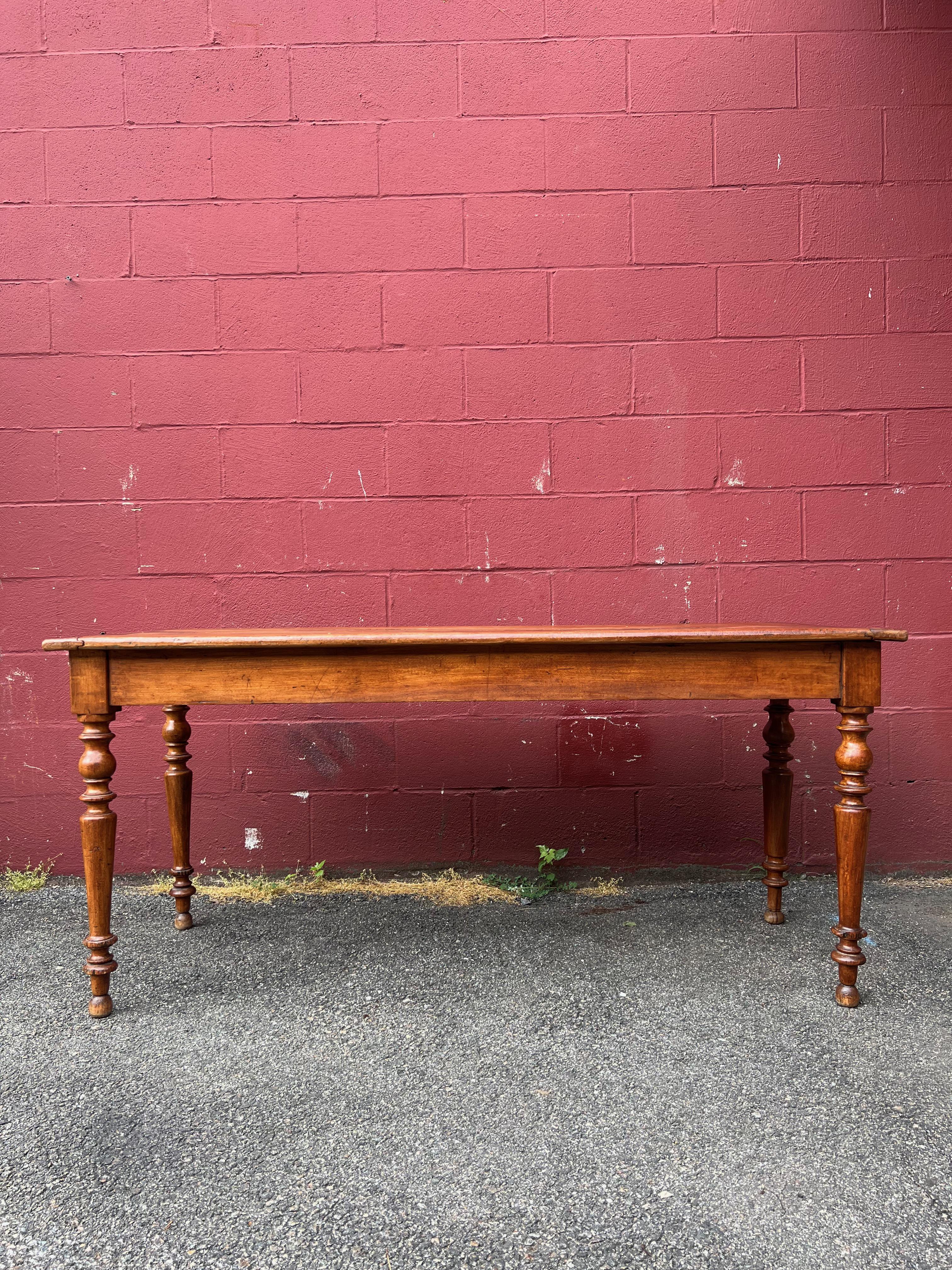 This large French work table is a stunning piece of craftsmanship constructed from beautiful cherry wood. The original rich patina gives the table a charming vintage feel that will add character and warmth to any space. The top of the table is