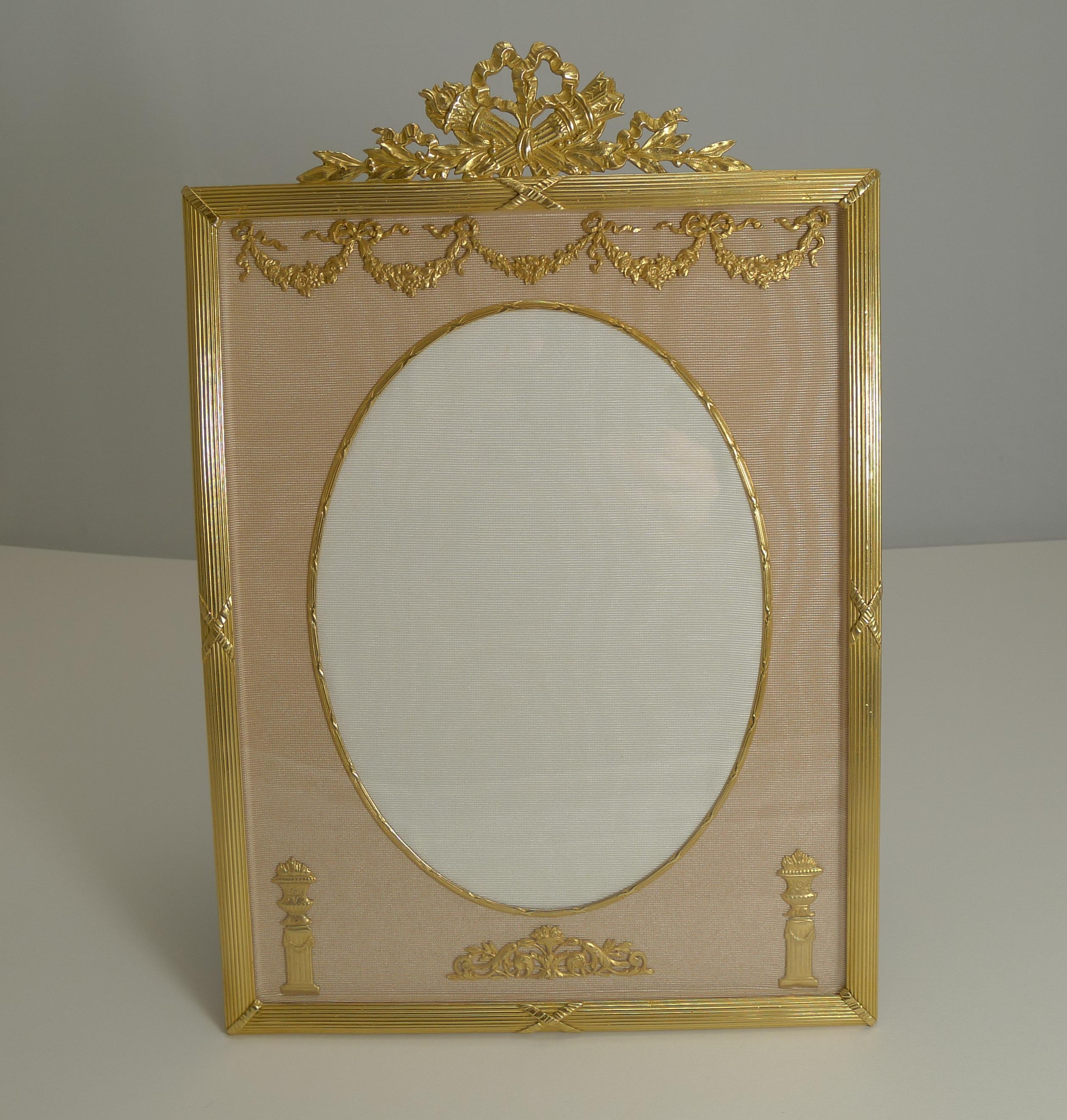 A magnificent and grand photograph frame; if you are looking for a statement piece, this may very well be it.

Made from ormolu or gilded bronze, it has been meticulously restored to it's former glory with a bright patina, clean silk taffeta and a
