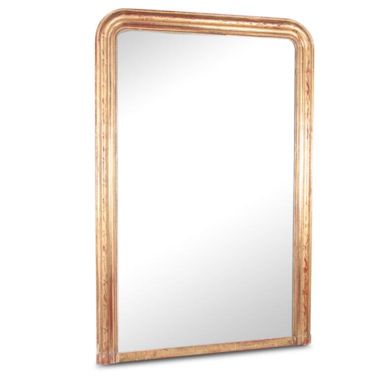 A very large 19th century French Louis Philippe gilt-framed mirror with original contrasting burnished and matt gilded floral details to the simple molded frame. Original glass in very good condition and with a lovely flecked patina throughout.
