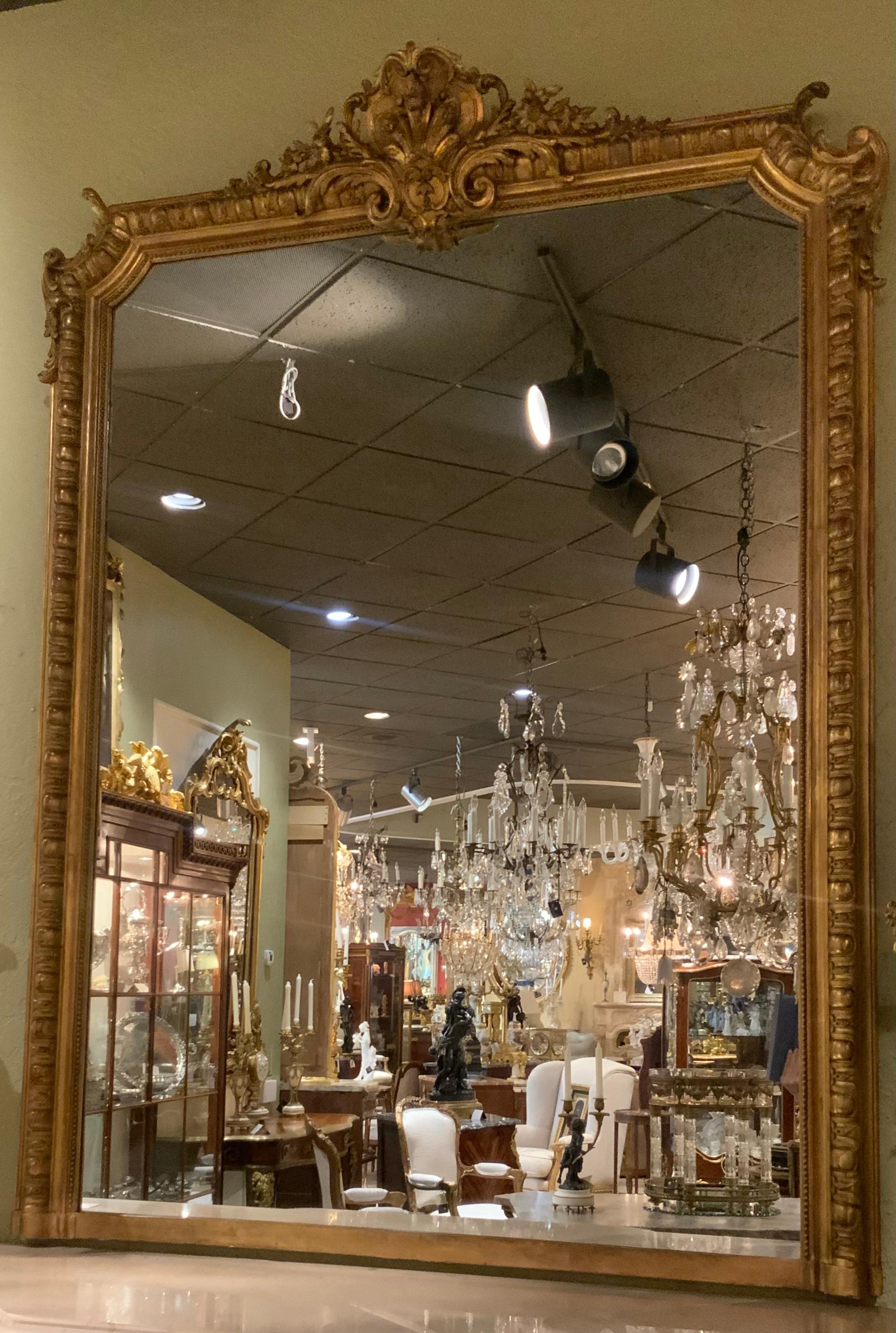 This majestic giltwood mirror is large in size and the carving
Is well done and in original condition. The gilding is a soft 
Gilt gold hue also in original condition. The crest has a cartouche 
Decorated with scrollwork and sprays of flowers. The
