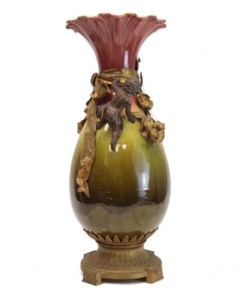 A large French glazed ceramic and gilt bronze footed vase, late 19th century. A beautiful transition of red, yellow, green to the vase with a flower petal rim. Applied cherubs throughout. Weight approx., 14 lbs. 



Measures: Approx., 8