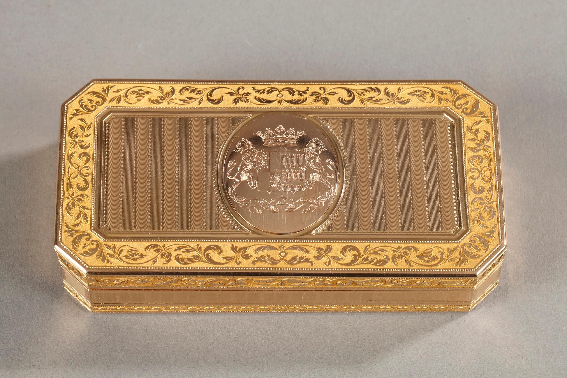 Large rectangular snuffbox with angled corners sides. The hinged lid is embellished with a guilloche pattern with alternating parallel and horizontal strips of matt and shiny gold. In the center of the lid a medallion presents the coat of arms of an