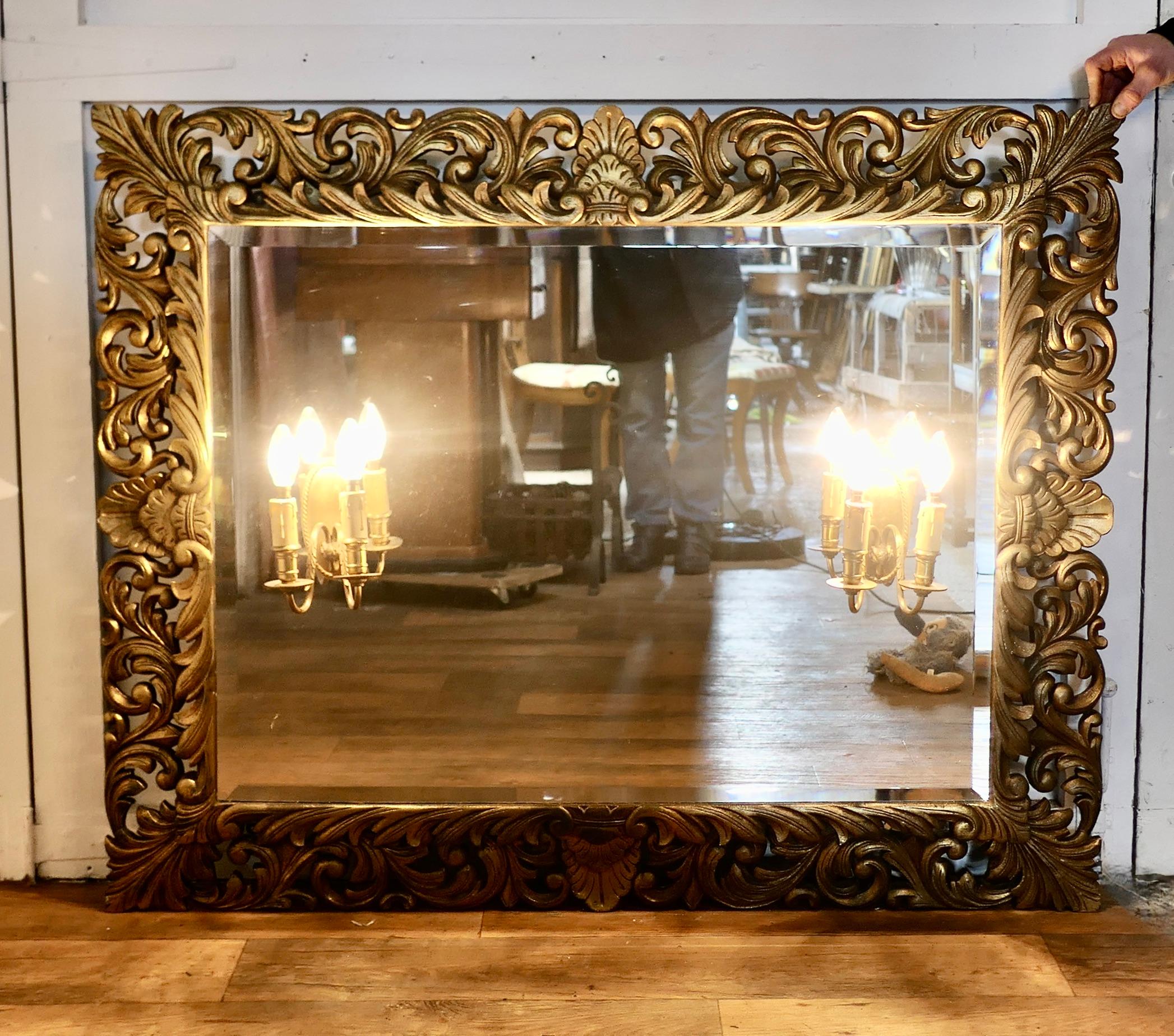 Large French Gothic Gilt Overmantel Mirror with Twin Sconces 

The 6” wide Carved Mirror Frame has pierced carving with acanthus leaves all the way around,  on the glass there are 2 twin brass scones, these have ram’s heads set in the brass.
 The