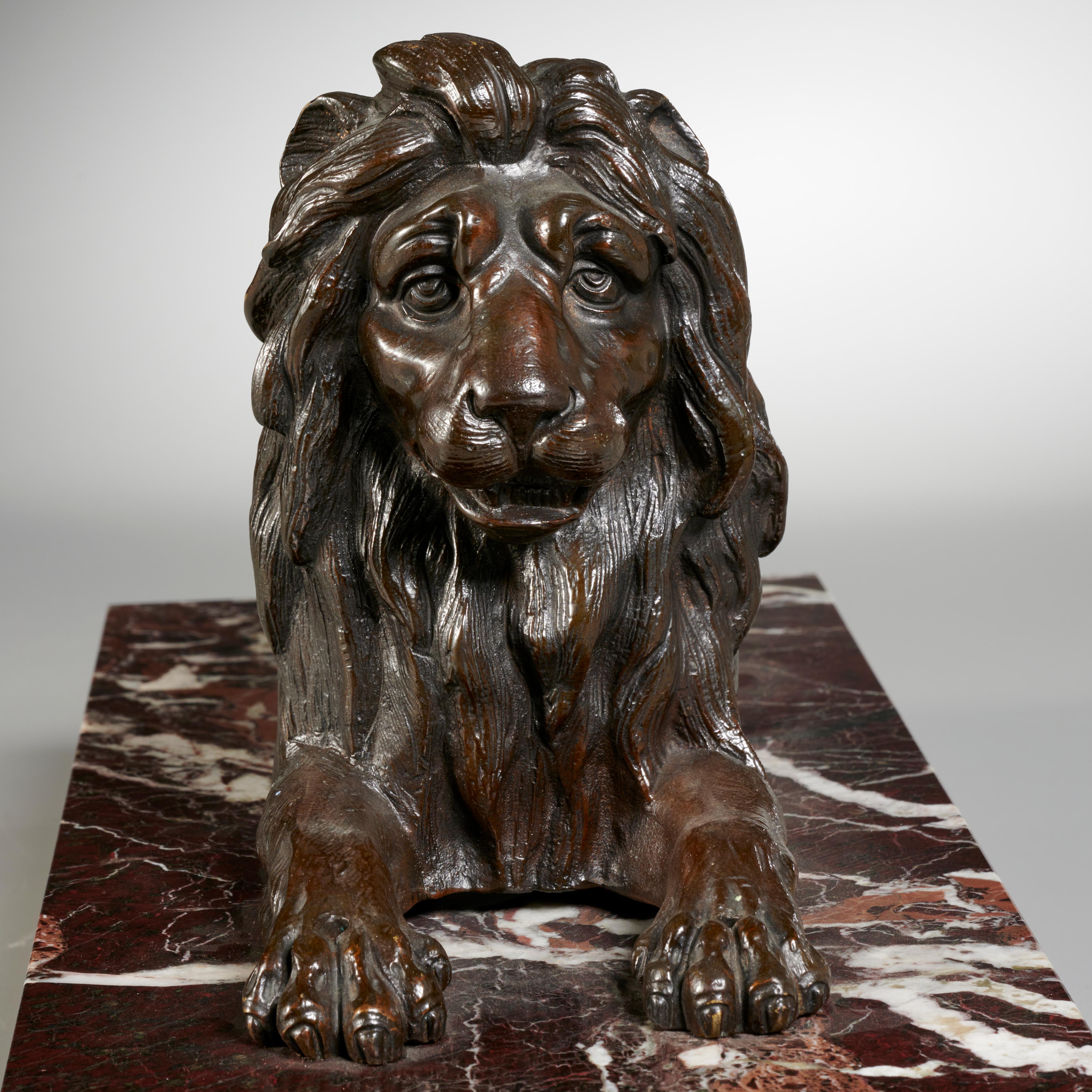 Sculpture en bronze d'époque Grand Tour représentant un lion reposant sur un socle en marbre rosso levanto. France : vers 1850.