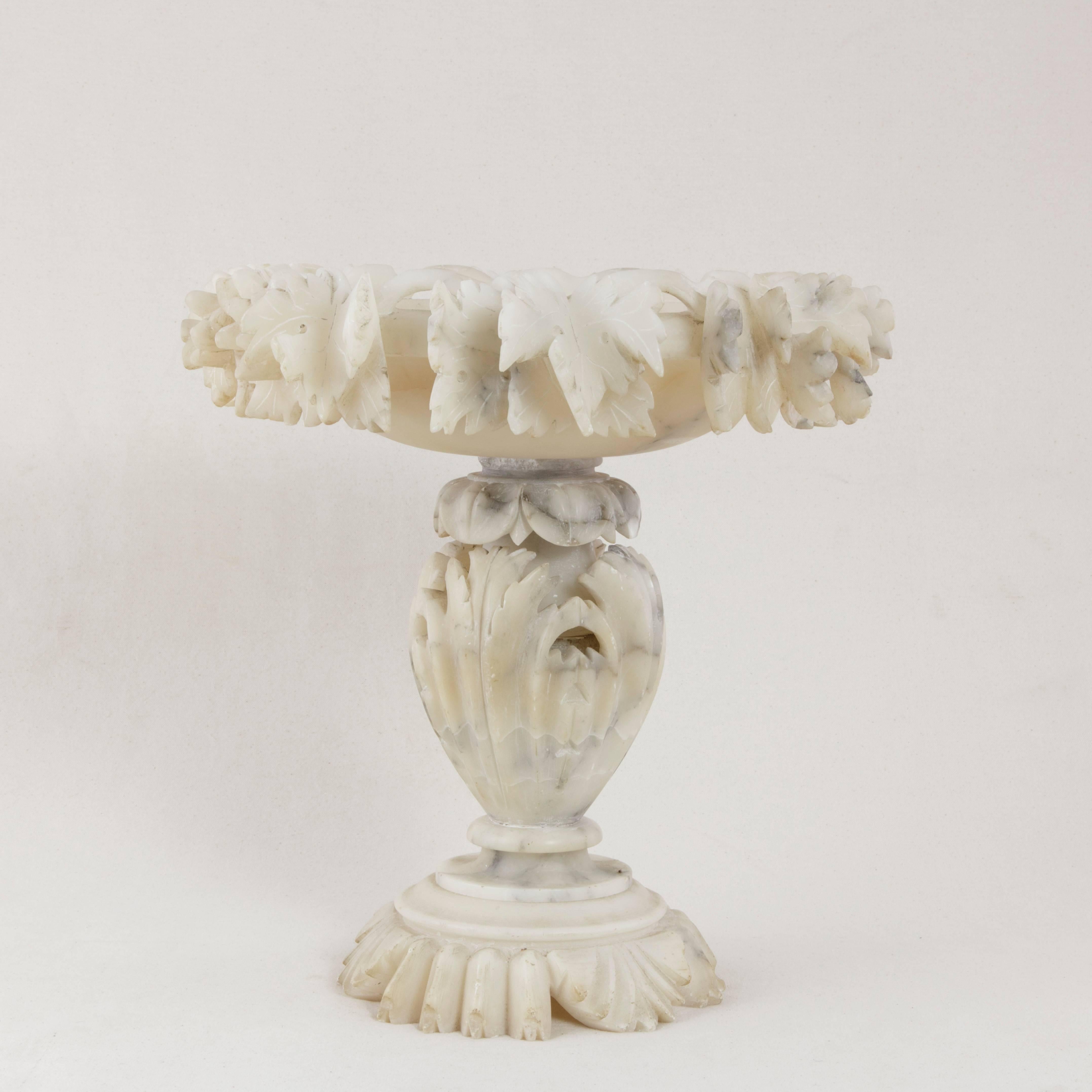 This large-scale French alabaster compote from the turn of the 20th century features deep relief hand-carved detailing of grape vines and leaves around the rim. Stylized leaves form the carved base and stem. Originally used to serve candies, fruits,