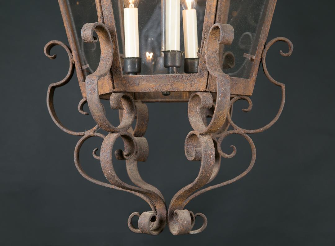 Questa fantastica lanterna a sospensione esagonale in ferro battuto presenta sei vetri e tre luci centrali che scendono da uno stelo centrale. Questo pezzo d'antiquariato francese risale al XIX secolo ed è impreziosito da una lavorazione a volute