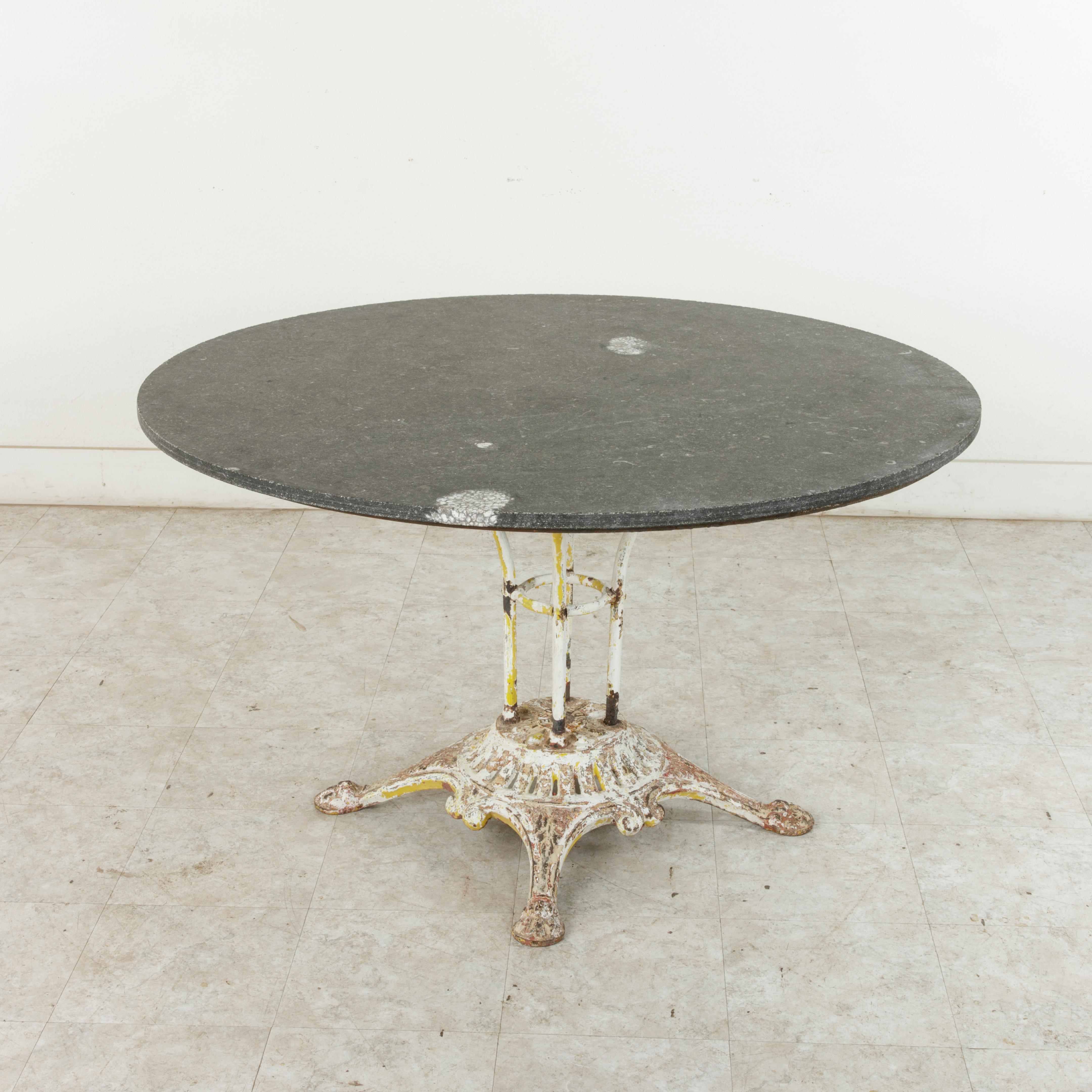 This large French iron garden table from the turn of the 20th century features an impressive 49 inch diameter blue stone top with embedded white fossils. Of an unusual large scale, the stone top is supported by four iron rods mounted on an iron