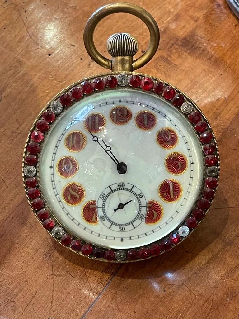 Large French Brass and Crystal Ball Clock circa 1900, the case perimeter set with red and clear paste, centering white enameled dial with gilded Arabic numerals on red; marked: France; H4