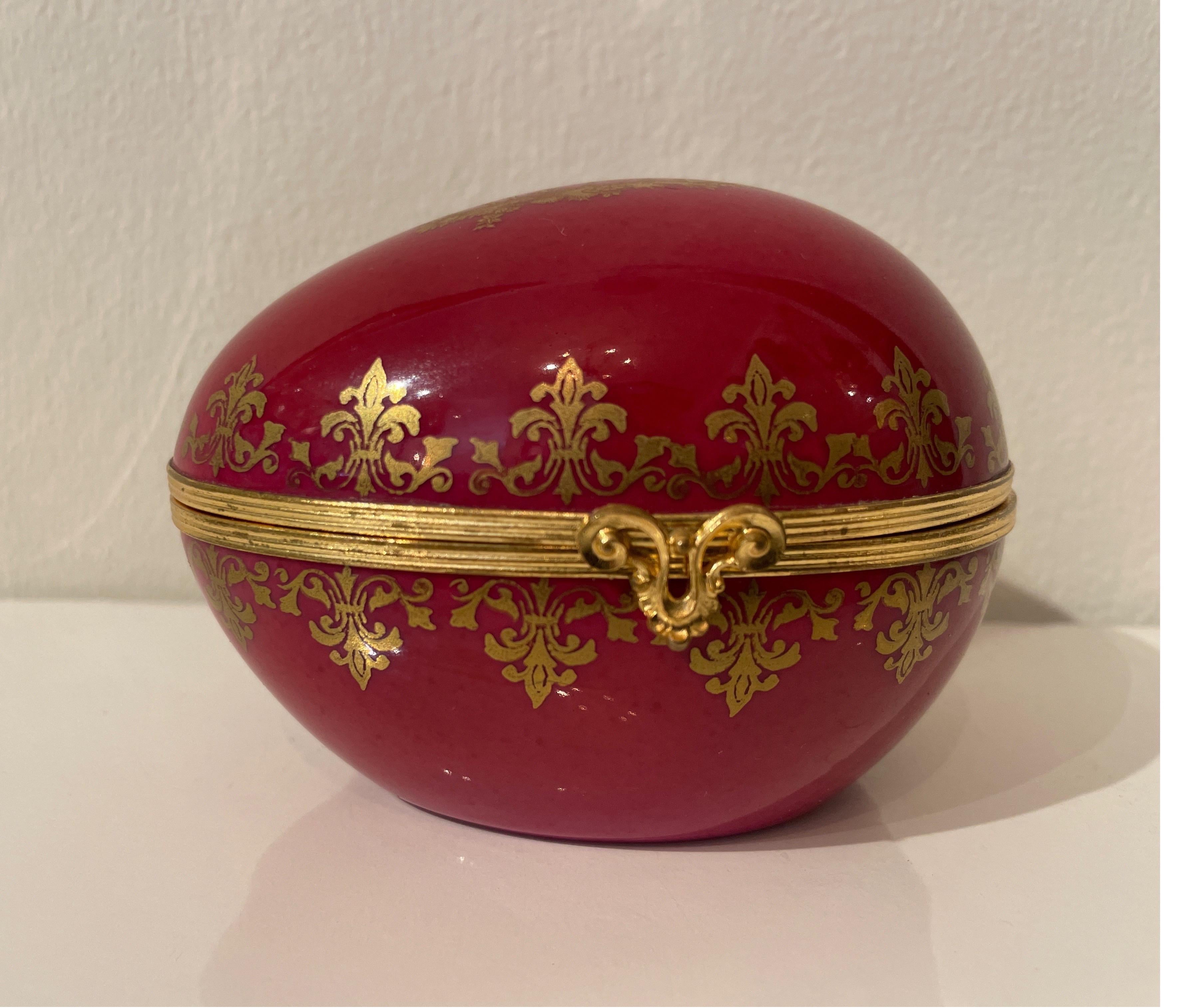 Large porcelain hand painted Limoge box in the shape of an egg. Trimmed in a gilded bronze. Egg is painted a rich burgundy color with gold accents.