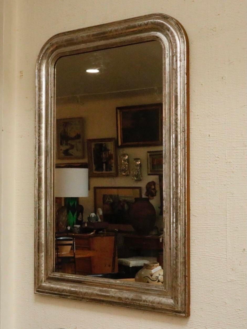 A large French Louis Philippe wall mirror. The frame has an arched top with a cross hatched patinated silver-leaf finish. Quite a statement piece!
