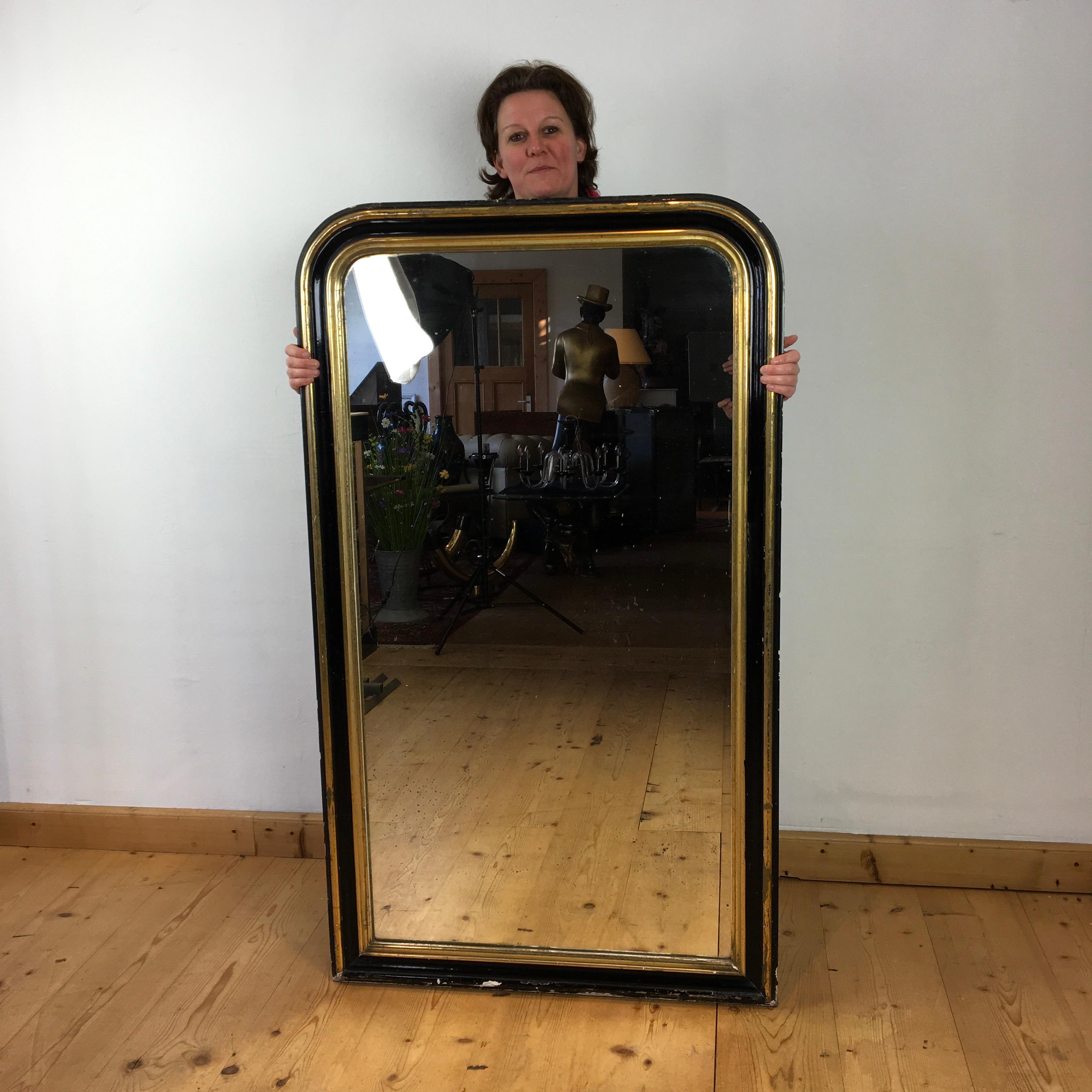 Large sized antique French Louis Philippe mirror. 
This authentic French antique mirror can be used as a floor mirror, wall mirror or mantel mirror. 
It's a black and gold antique mirror with lots of patina and charming traces, 
as well on the