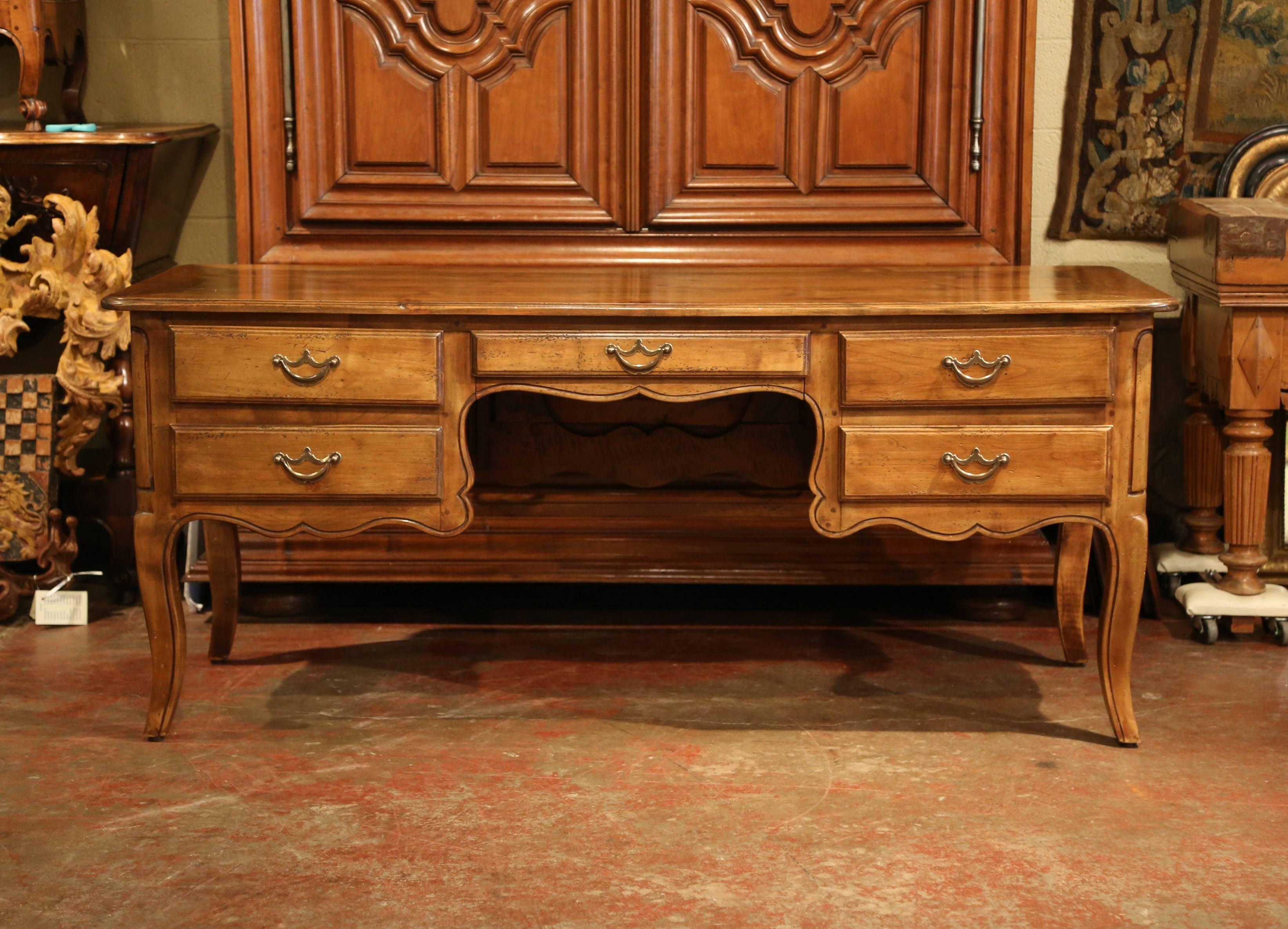 This elegant antique fruitwood desk was created in the Poitou region of France, circa 1980. Made of old cherry timber, the large writing table sits on four cabriole legs and is shaped all the way around; the desk has five drawers with patinated