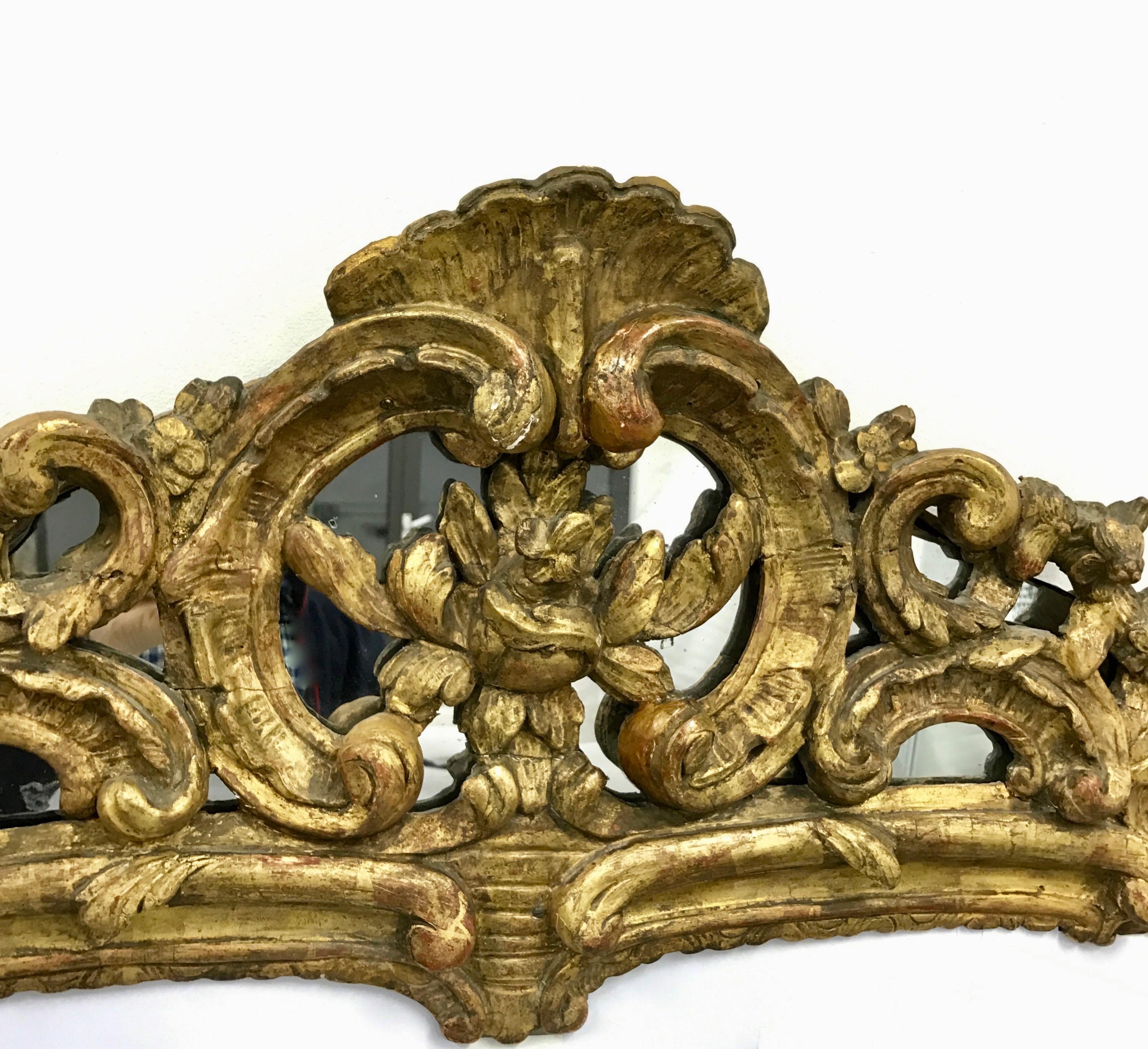 A very large French Louis XV carved and gilt wood mirror with richly shell carved crest and flower decoration. 
Generally in good condition for its age, however, some parts of this mirror has been repaired by its previous owners and very delicate.