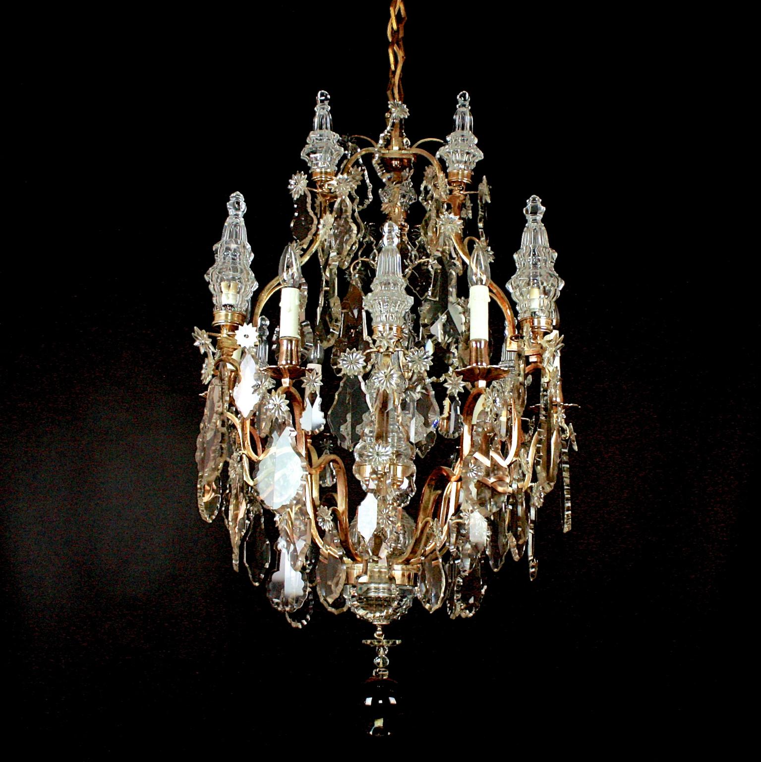 A large Louis XV style 16-light crystal-cut chandelier decorated overall in scalloped Baccarat pendalogues with stellar jewels and impressive differently sized moulded baluster pinnacles. The open pear-shaped frame supports two tiers, six scrolling