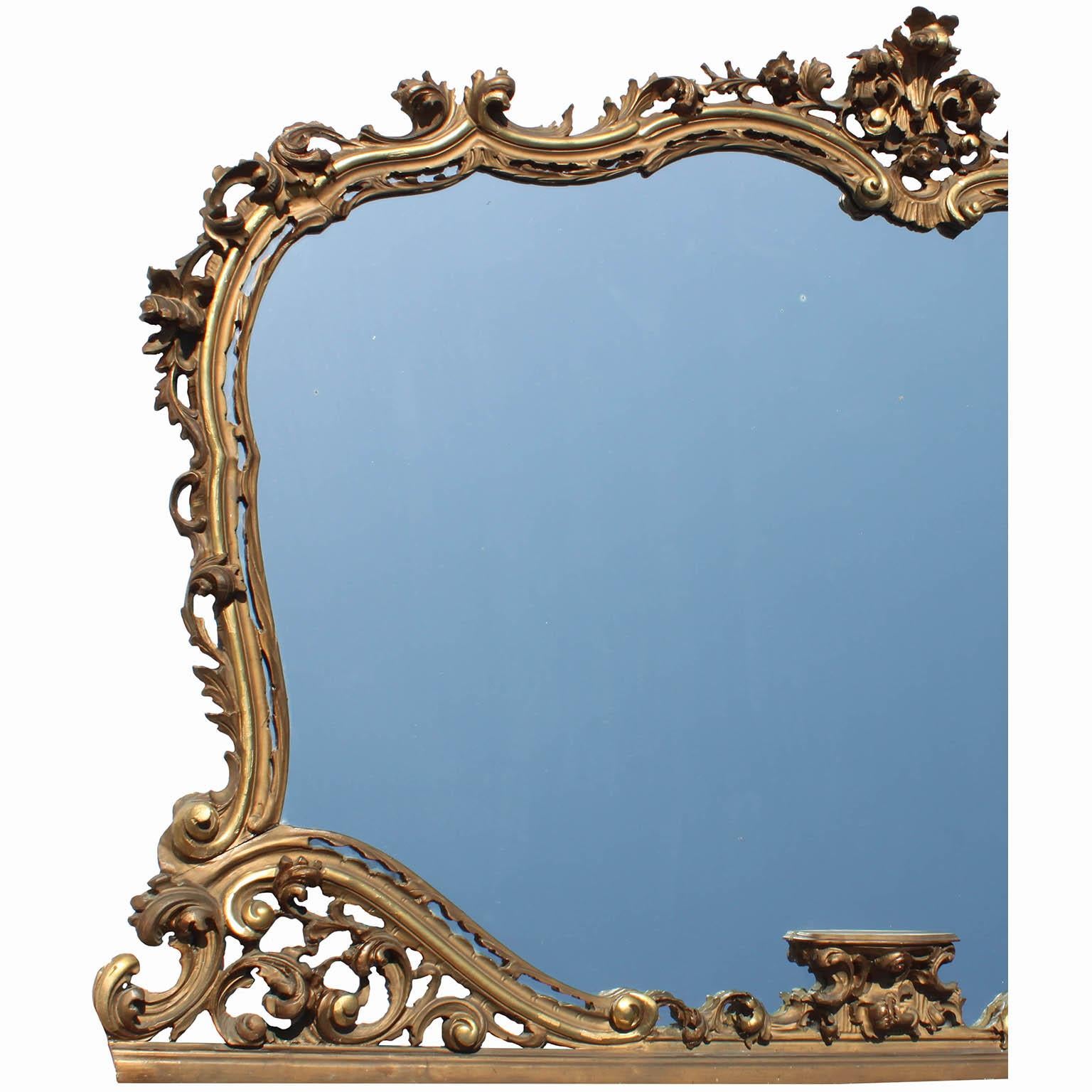 Großer französischer Spiegelrahmen im Stil der Belle Époque im Louis XV-Stil mit kunstvollen Schnitzereien aus vergoldetem Holz mit Übermantel. Der kunstvoll geschnitzte Rahmen ist mit einem Blumen-Blatt-Arrangement gekrönt, das durchbrochene