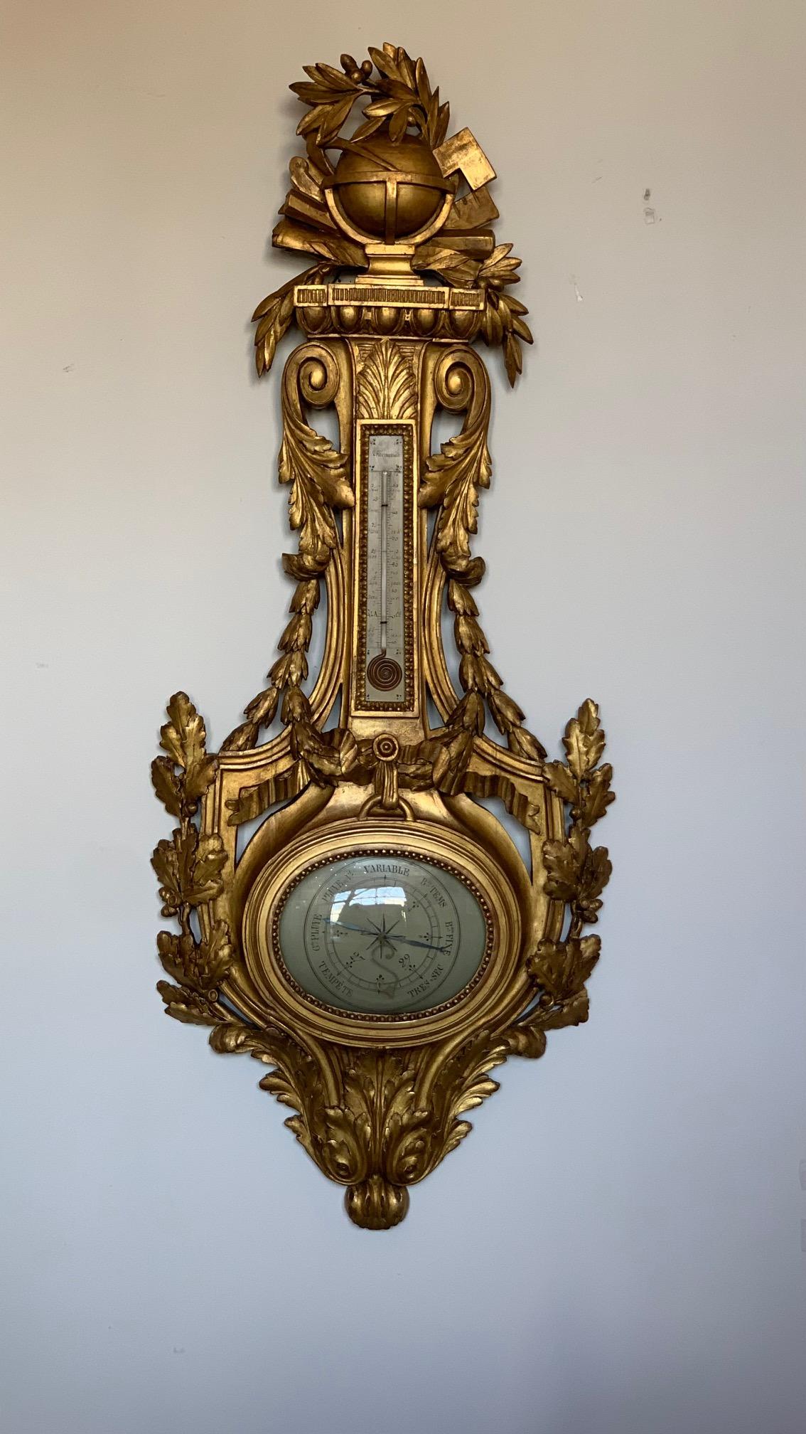 A very large French Louis XVI style baromete and termometer in gilt wood with a covex glass face. This highly decorative piece has carved oak leaves and acorns as well as acanthus leaves and a globe at the top. It appears to be late 19th century.