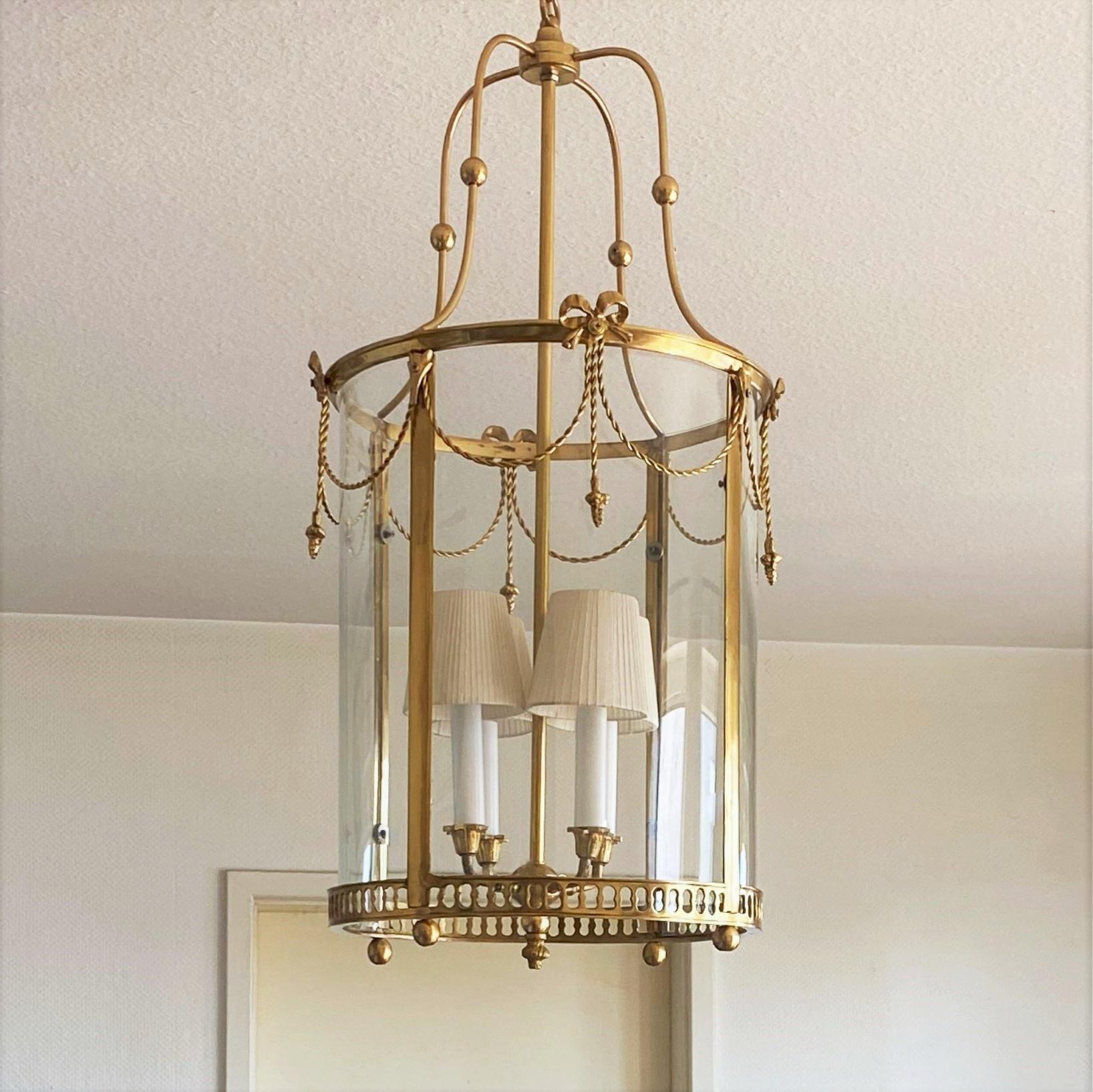 A very elegant gilt bronze and brass mounted cylindrical lantern with a central four-light candelabra cluster, France, 1920-1930. Finely handcrafted, clean lines and modern design inspired by Louis XVI style. Four original curved crystal glass
