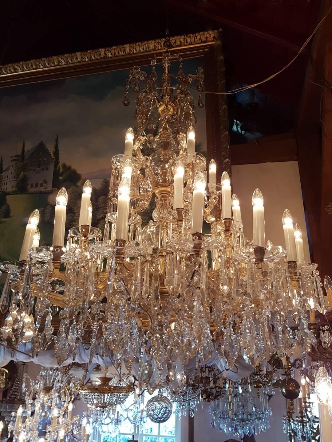 Unique and authentic large French Maria Theresia chandelier with 30 lights. Beautiful crystals with big drops and small glass ornaments to the side of the arms. In the centre beautiful shape of glass bowls and bottles. Five-light points have been