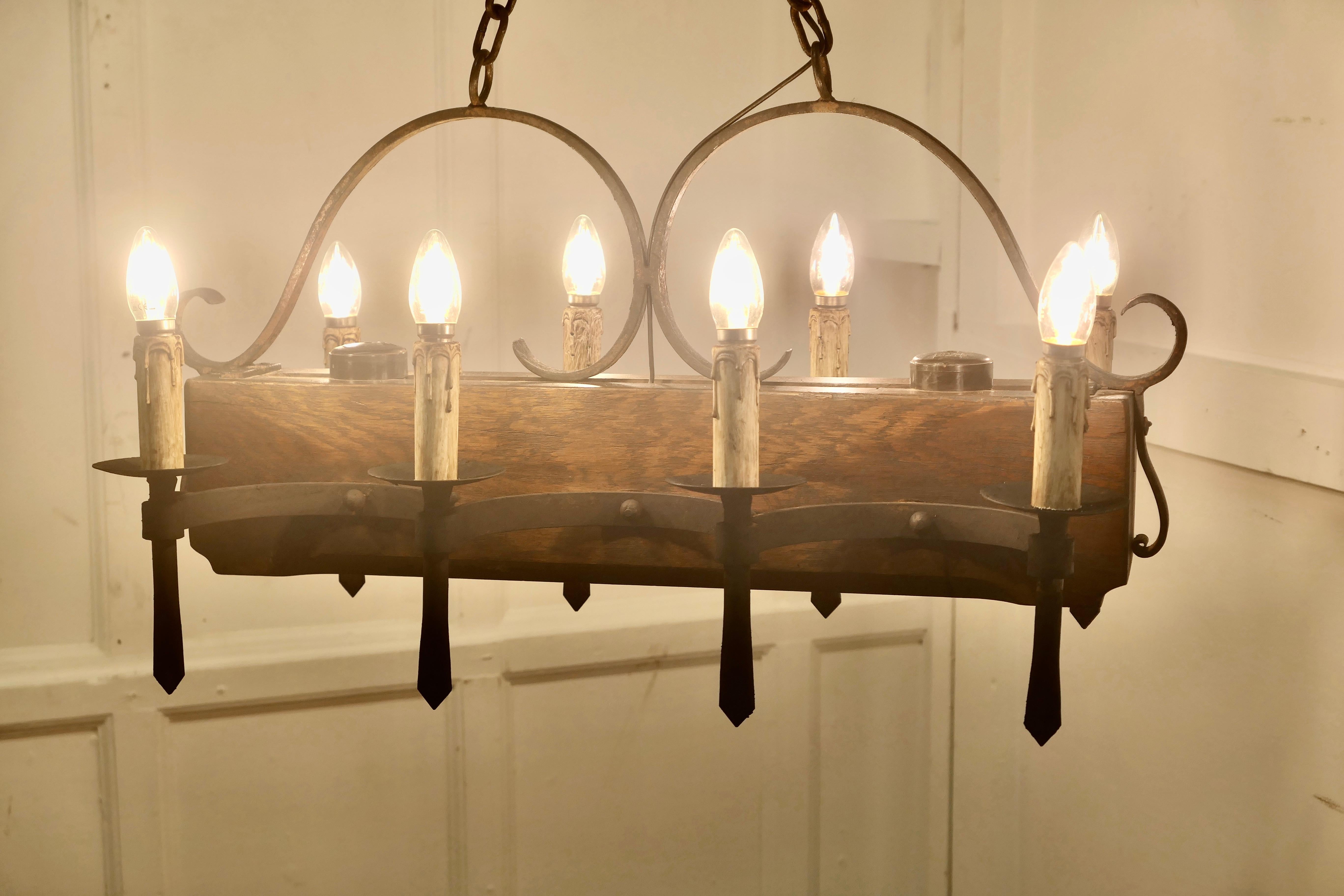 Large French Medieval Rustic Chandelier

This is a Large French Medieval style Rustic Chandelier, it is very heavy and hangs on a long chain, it has 6 hand-forged iron light sconces set  on walnut  
The light is 29” high, 30” long and 17” wide, it