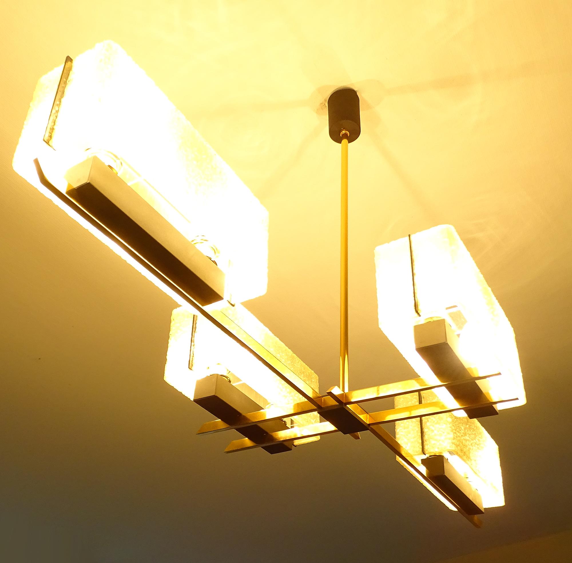 Exceptionnal large linear chandelier by the 1960s French lighting designer Maison Arlus (Arts et Lustre) featuring four rectangular off-white wavy and textured fiberglass light shades with a black perspex accent, placed on a brass cross shaped