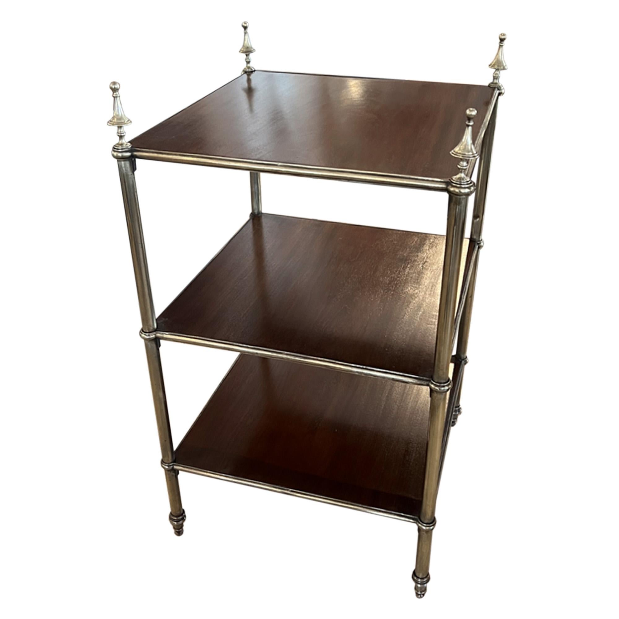 Il s'agit d'une très belle table d'appoint simple, fabriquée en France dans les années 1950. 

Les trois niveaux sont en acajou poli, soutenus par des colonnes en laiton qui se terminent au sommet par quatre impressionnants fleurons en forme de