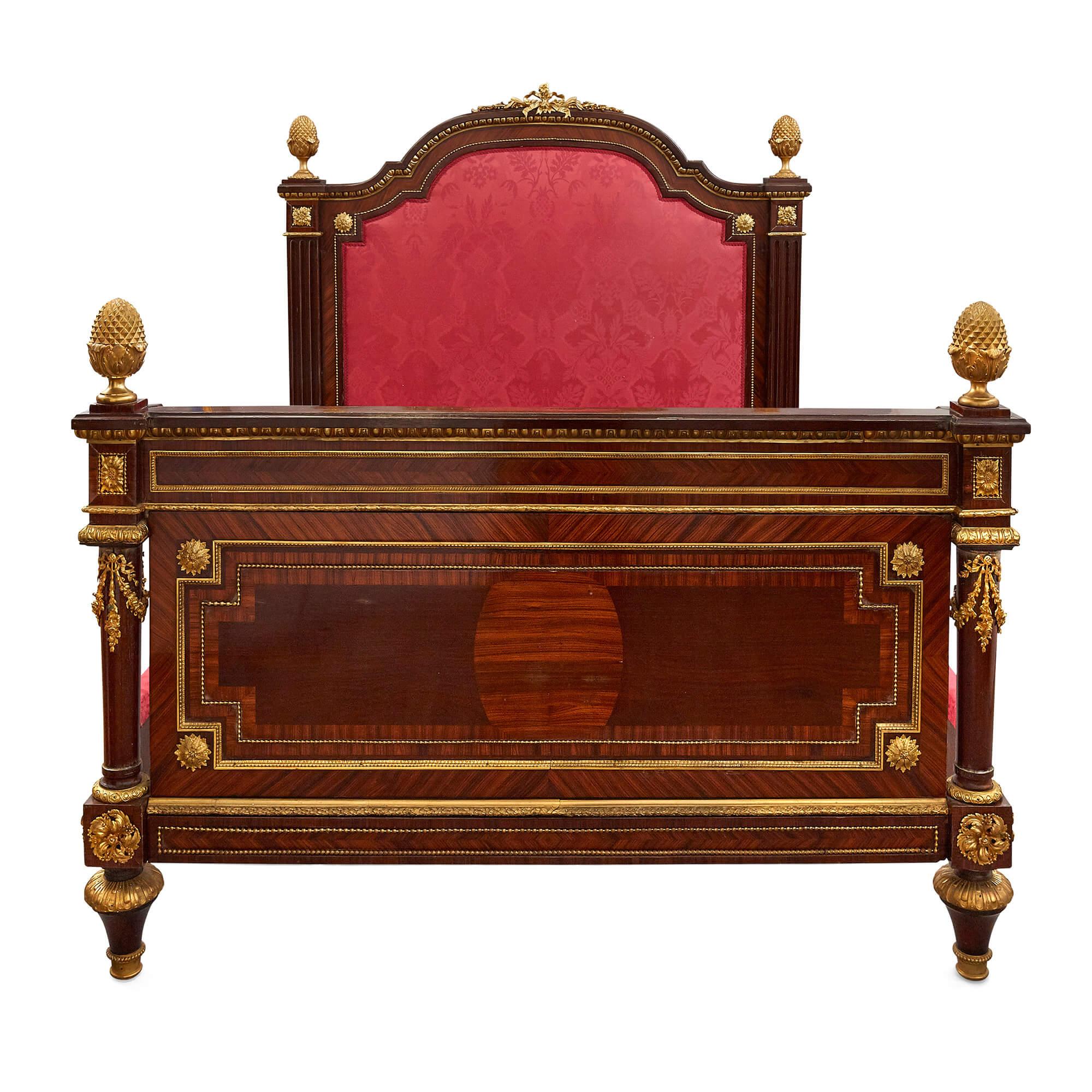 Large French neoclassical style gilt bronze mounted bed
French, late 19th century
Measures: Height 143cm, width 147cm, depth 225cm

This impressive bed is crafted in the neoclassical style from wood, gilt bronze, and red velvet. The bed features