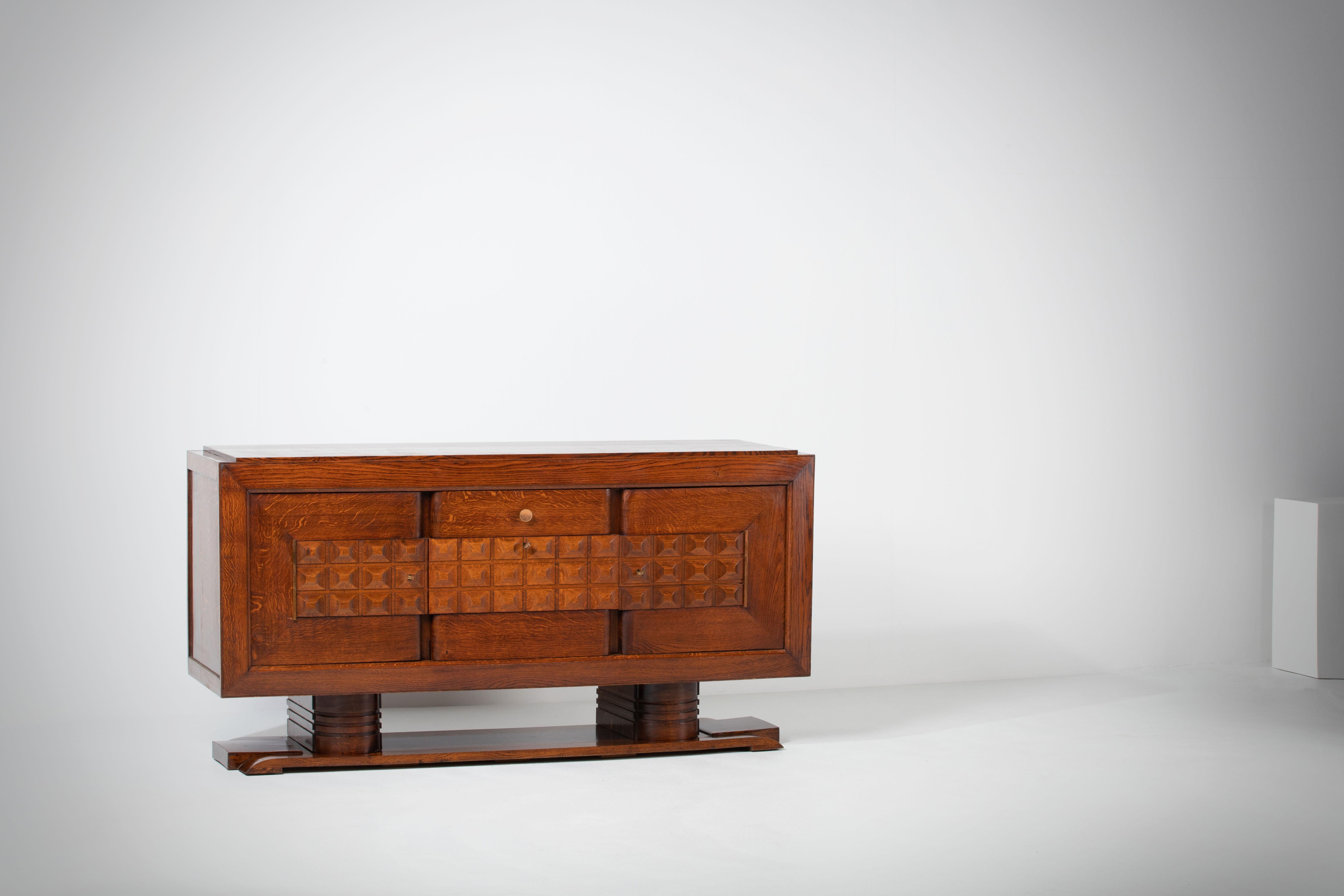 A large sideboard/credenza attributed to Charles Dudouyt. 
France, c1940s.
Consists of 1 central drawer and three storage compartments. The middle compartment has a flap door.
Inlaid wood center shelves, brass detailing and graphic design doors