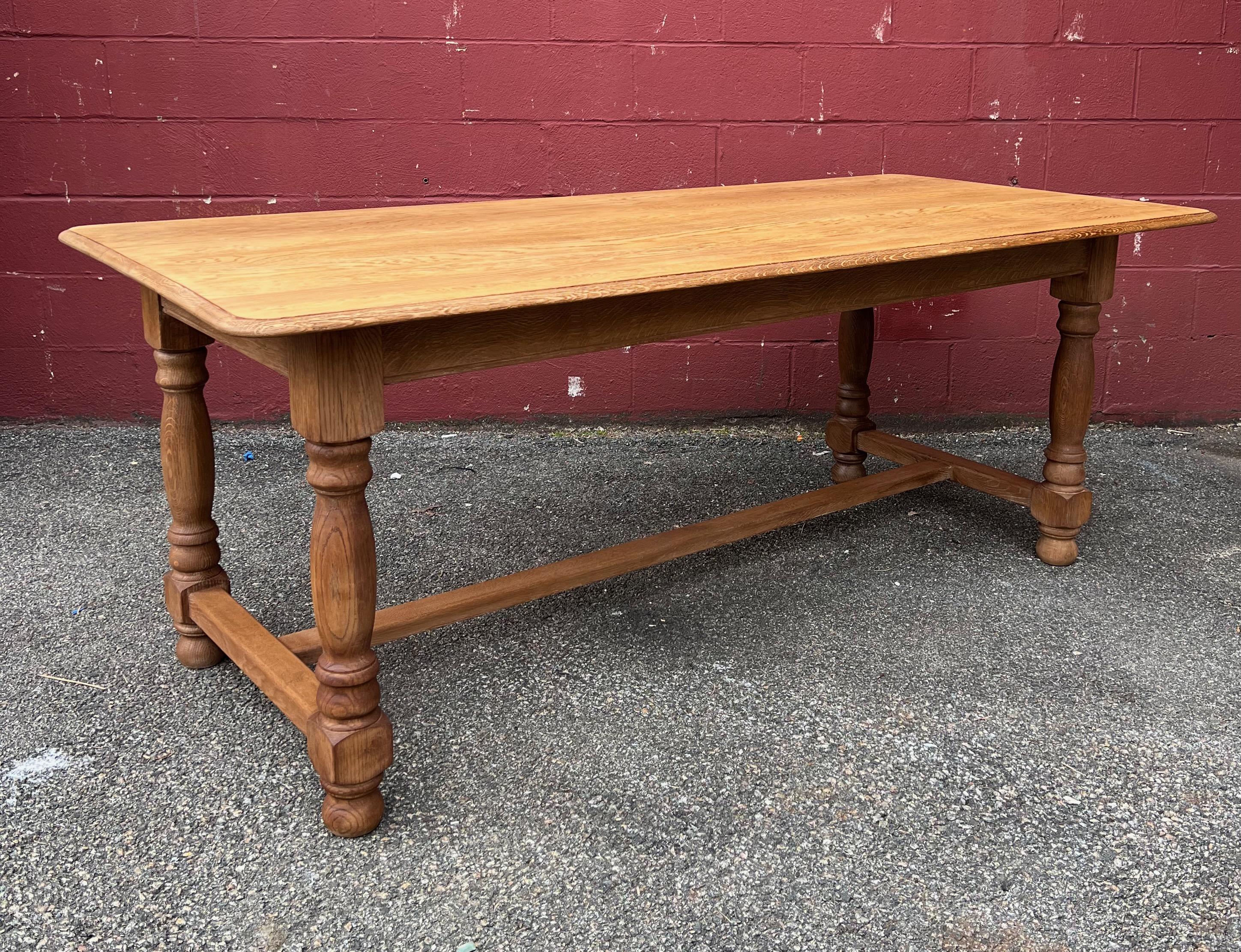 This large 1950s French oak dining or hall table features beautifully turned legs with a lower stretcher. Its sturdy construction makes it perfect for daily use, built to withstand the test of time while providing an enduring sense of elegance and