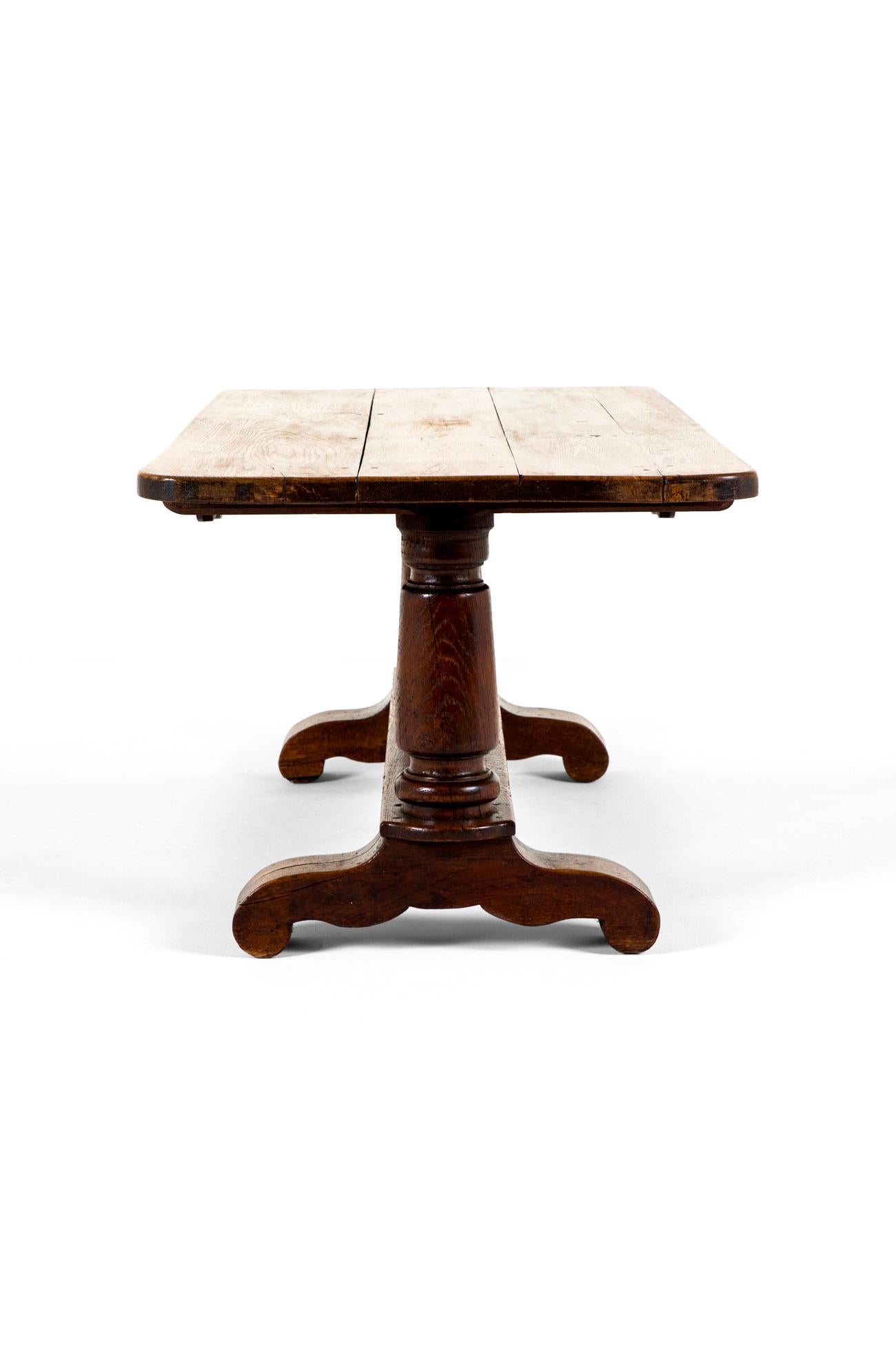 Grande table de réfectoire en chêne avec un plateau en planches épaisses.

Sous la table se trouve un élégant 