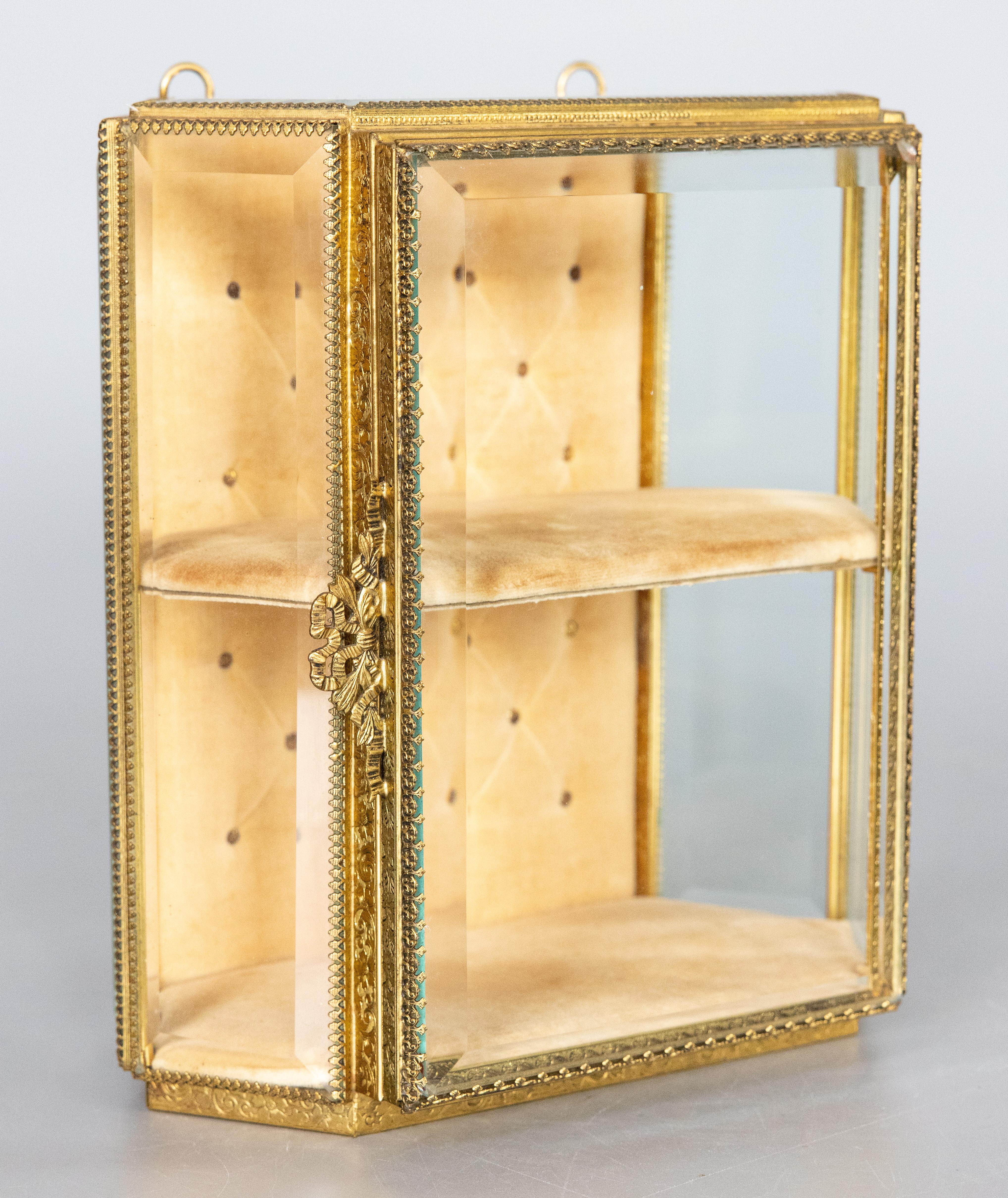 A stunning antique early 20th-Century French wall mounted gilt brass ormolu and beveled glass hanging jewelry casket box with hinged door. It's very rare to find one that hangs on the wall! This fine quality box has a two level compartment design