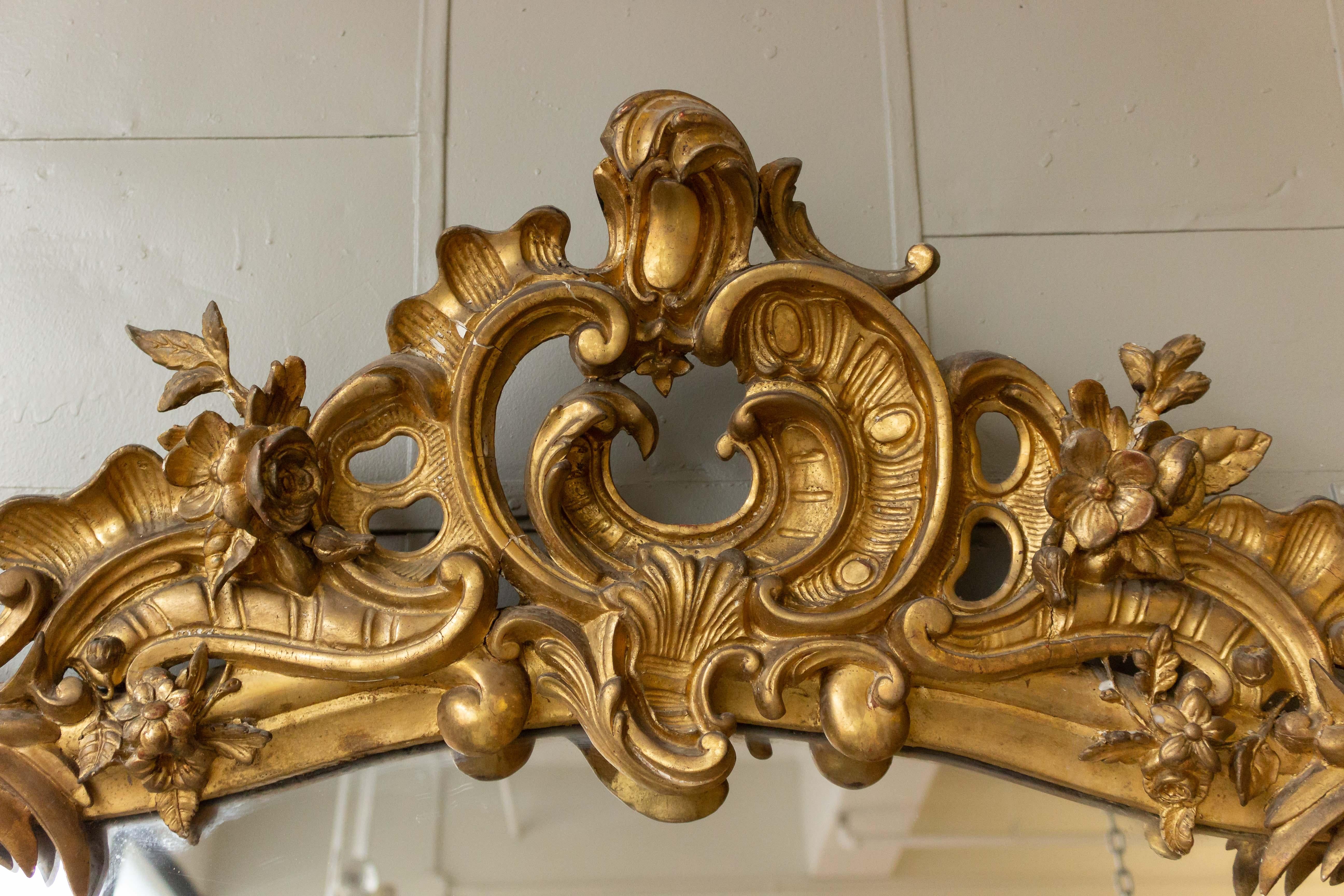 Very large and ornate gilt wood and plaster mirror in the Rococo baroque style with original mercury glass. The mirror is on good condition with minor losses to the frame. French mid-19th century.