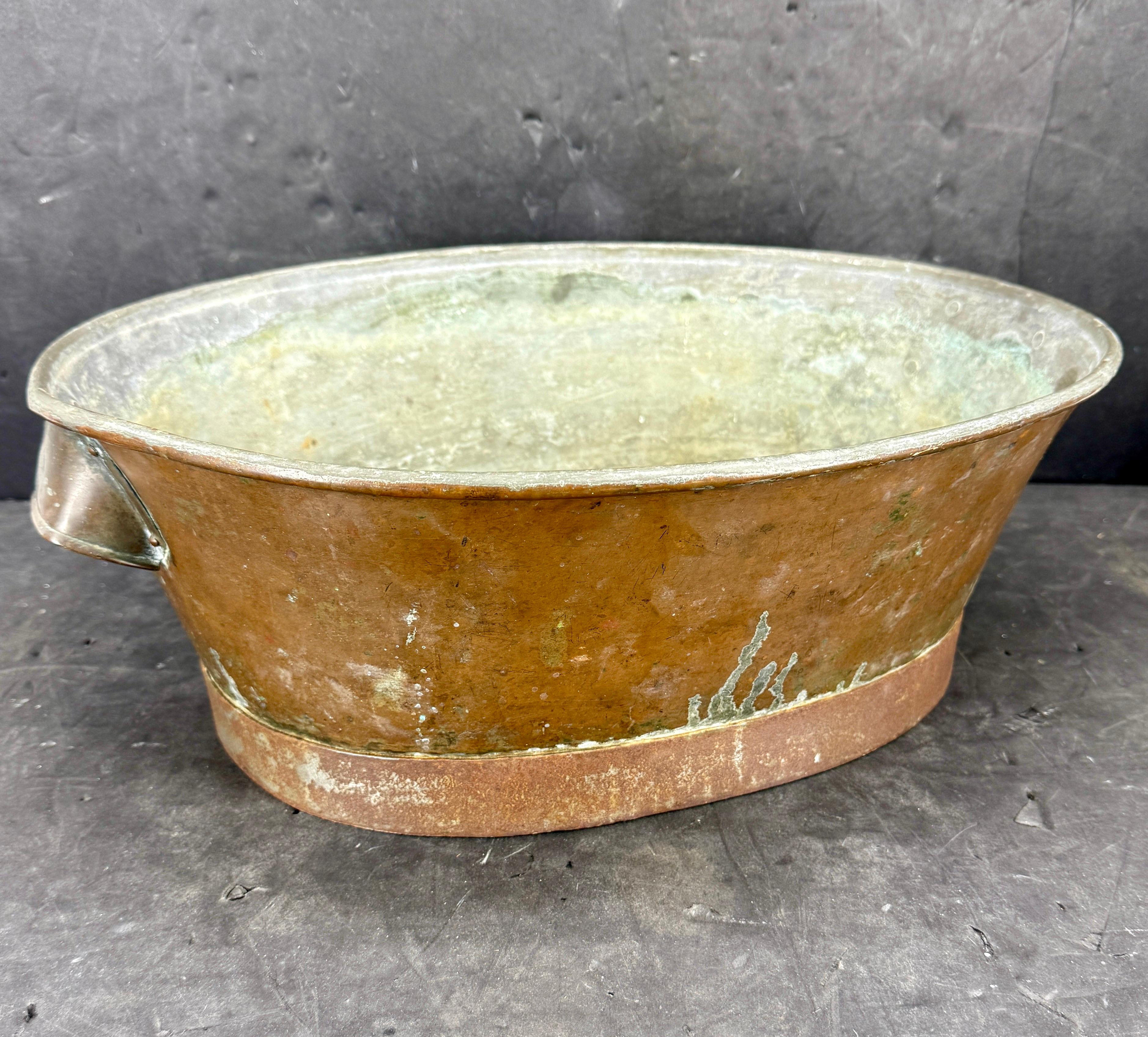 Questo secchiello vintage per champagne o vino con manici presenta un'affascinante finitura in ottone.  Come si vede in tutta Europa, questo secchiello fuso a mano è in grado di elevare qualsiasi occasione. La patina naturale di un pezzo di