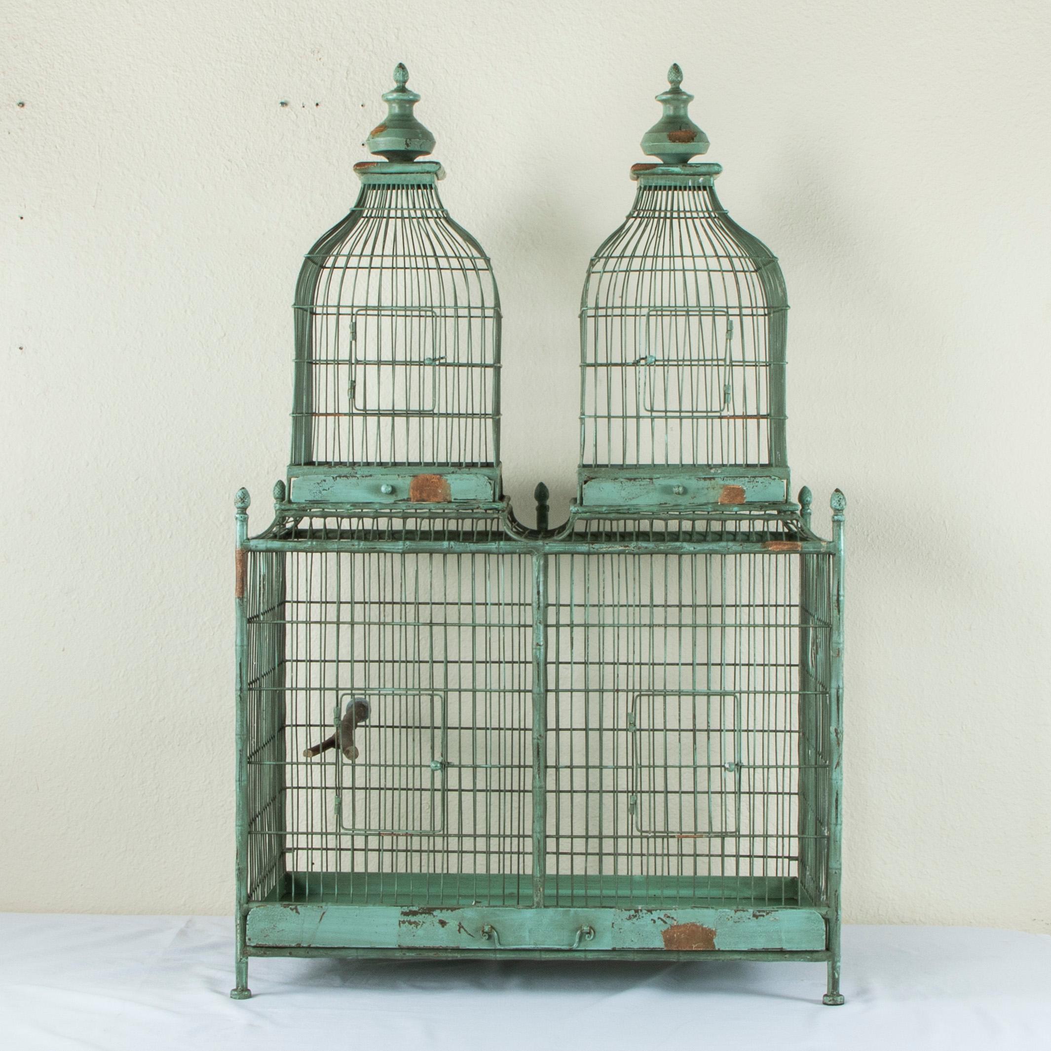 Found in Normandy, France, this very large painted metal and wire bird cage takes the form of a double roofed house and features faux bamboo detailing and pinecone finials. The lower compartment has a removable bottom, two doors, and a wooden perch.