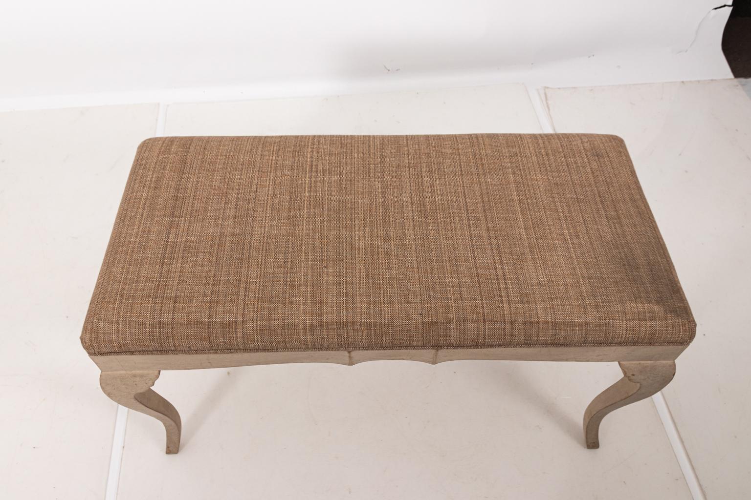 Large French Provincial style upholstered two seat bench in brown Belgian linen, circa 1900s. The piece also features a wood frame painted in off white and cabriole legs. Please note of wear consistent with age including distressed finish and minor