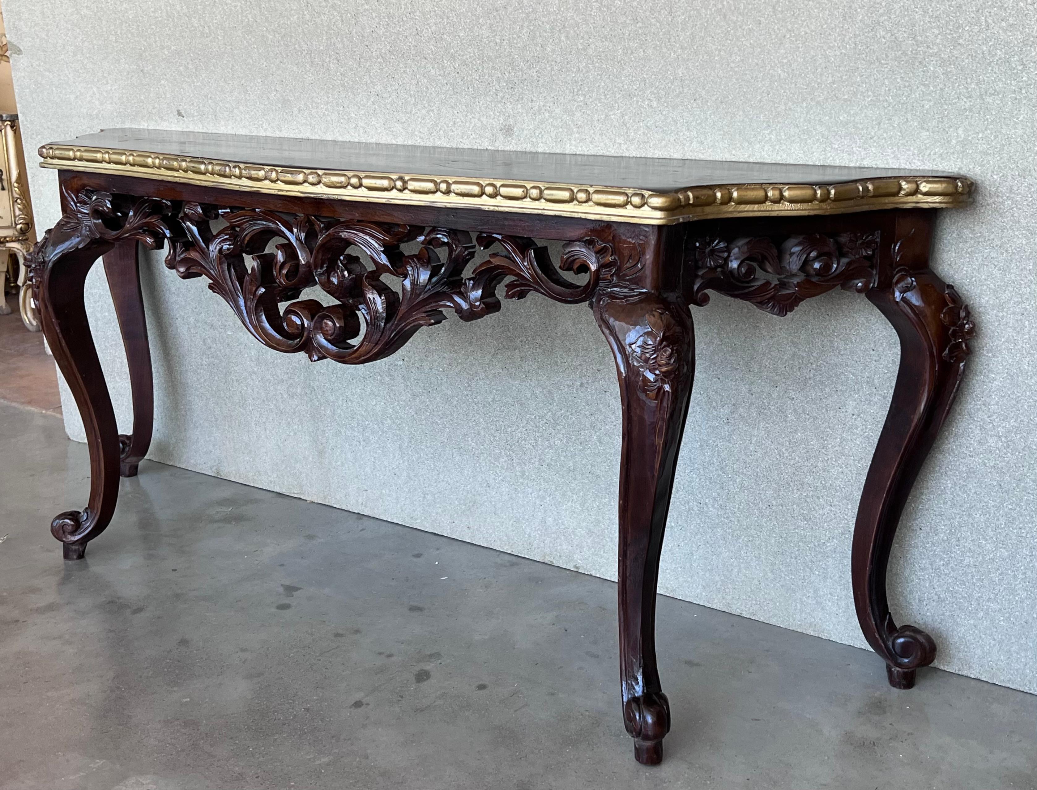 20th French Regency carved walnut console table with gilted edges 

20th century French Regence style beautifully carved with leaves walnut console. Wood top with carved front, over hand-carved frieze supported by four cabriole legs. Very massive