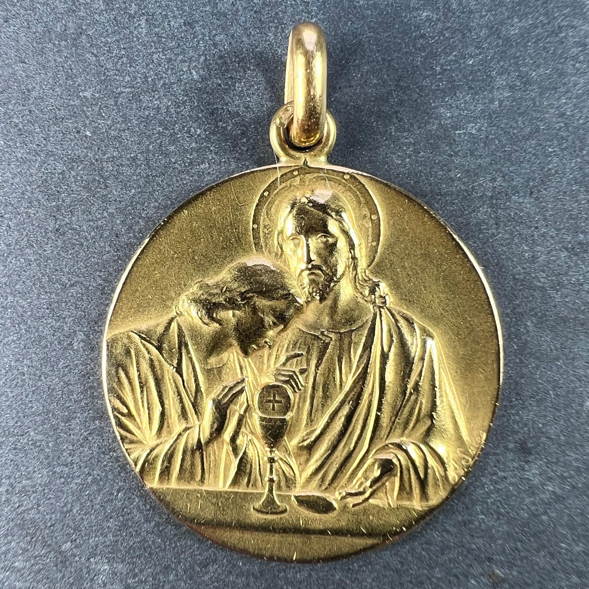 A large French 18 karat (18K) yellow gold charm pendant designed as a medal depicting Jesus preparing the holy communion at the Last Supper to one side. The reverse with a sheaf of wheat and a grapevine to the side of a chalice and wafer to