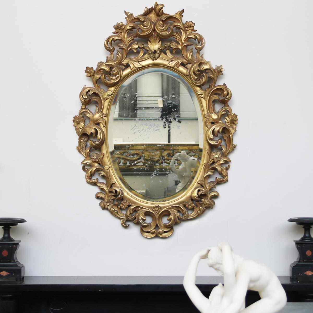 Beautiful and large mid-19th century, French Rococo gilded carved wood oval wall mirror. Showing great color and patina to the frame and a wonderfully distressed original mirror plate. 

Measures: 43