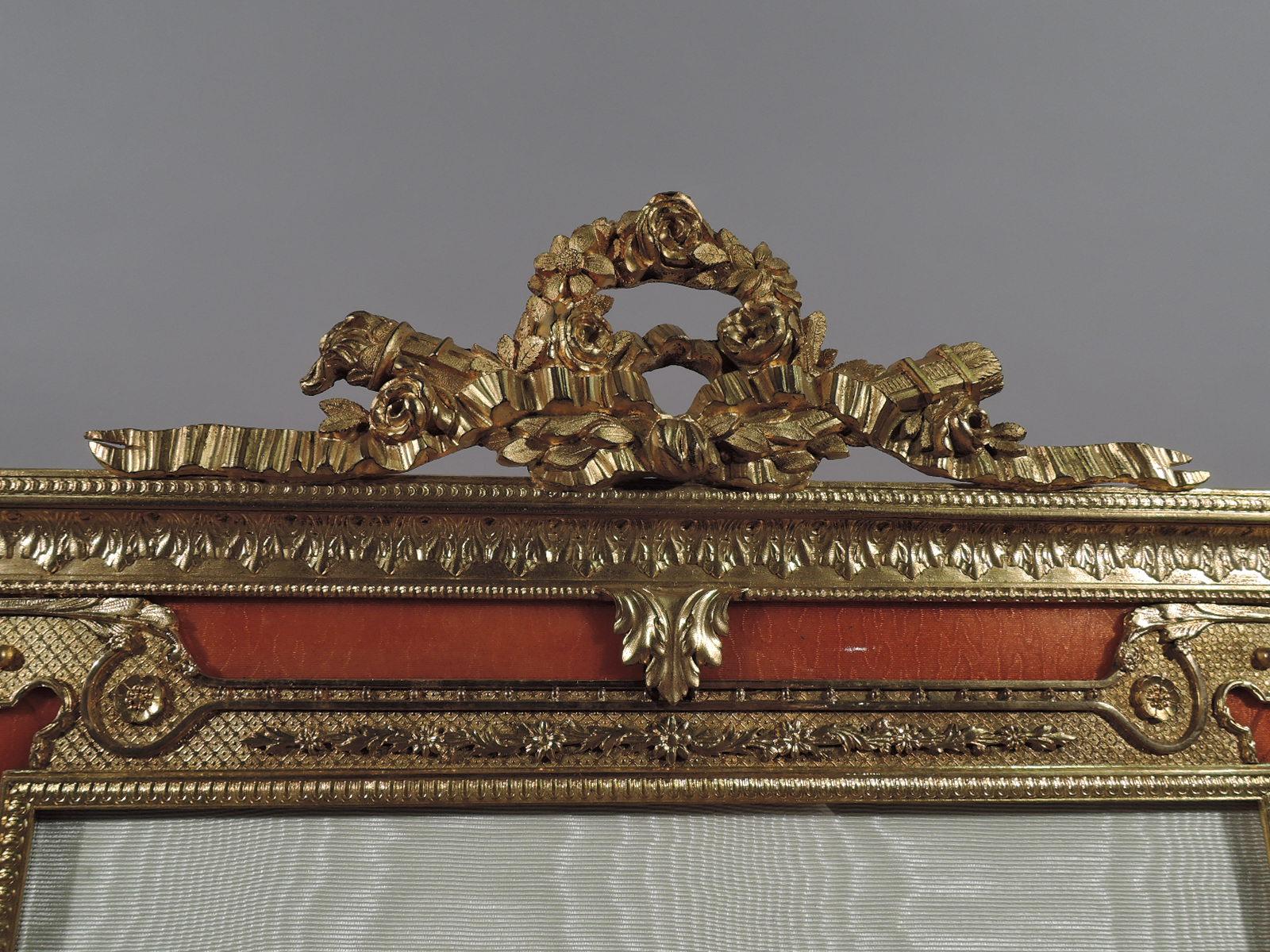 Turn-of-the-century French Rococo gilt bronze and pink guilloche enamel picture frame. Rectangular window in same surround with beading and leaf-and-dart ornament. Window bordered by diaper with applied flowers and leaves, and open block corners