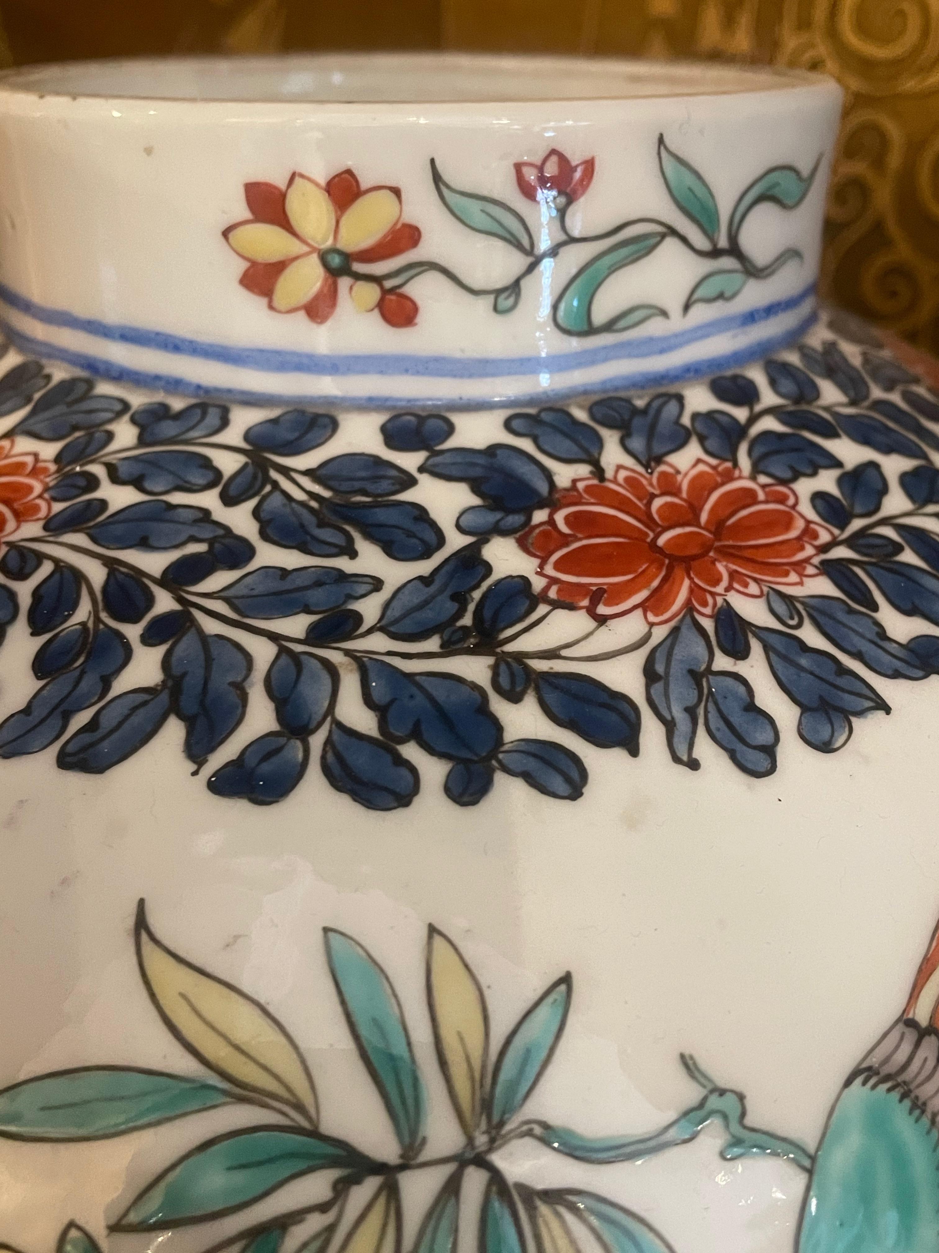 A large French Samson jar, circa 1880, decorated in the Japanese Kakiemon style. With a blue foliate design dotted with red flowers, marking out the borders between matching rural scenes of two brightly dressed figures under a flowering tree,