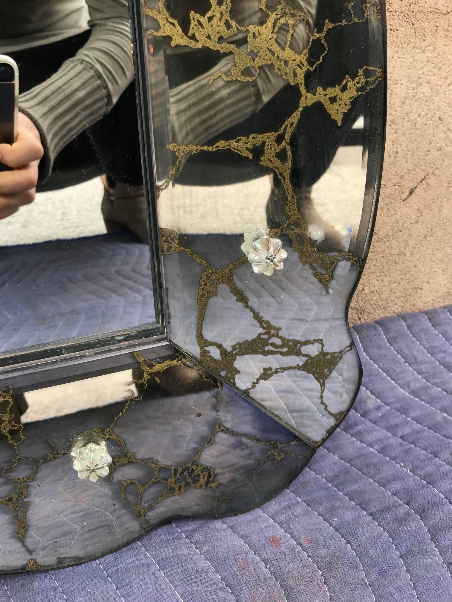 A large beveled and gilt serpentine mirror with original looking glass. Frame with patinated gold églomisé decoration.

Measurements:
Height: 61.5